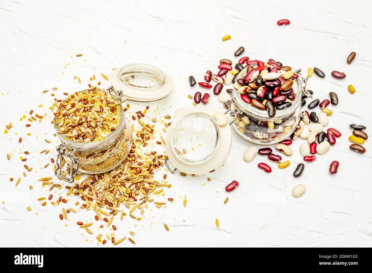 Mezcla de variedad de cereales y frijoles en tarros de vidrio. Conjunto de fuentes indispensables de proteínas para un estilo de vida saludable. Blanco putty fondo, espacio de copia Foto de stock