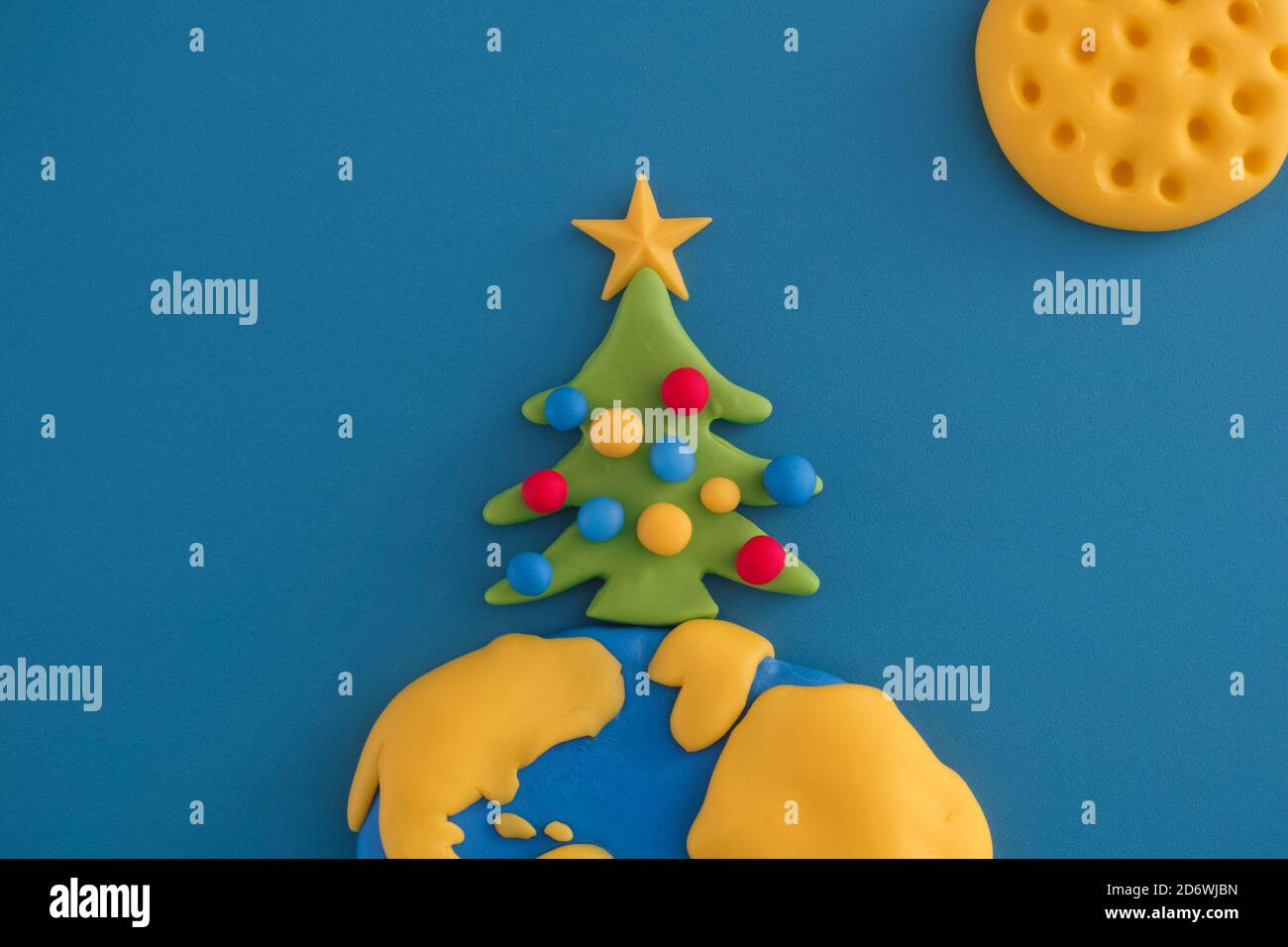 Un árbol de Navidad en la parte superior del planeta Tierra. La escena está hecha de arcilla polimérica. Foto de stock