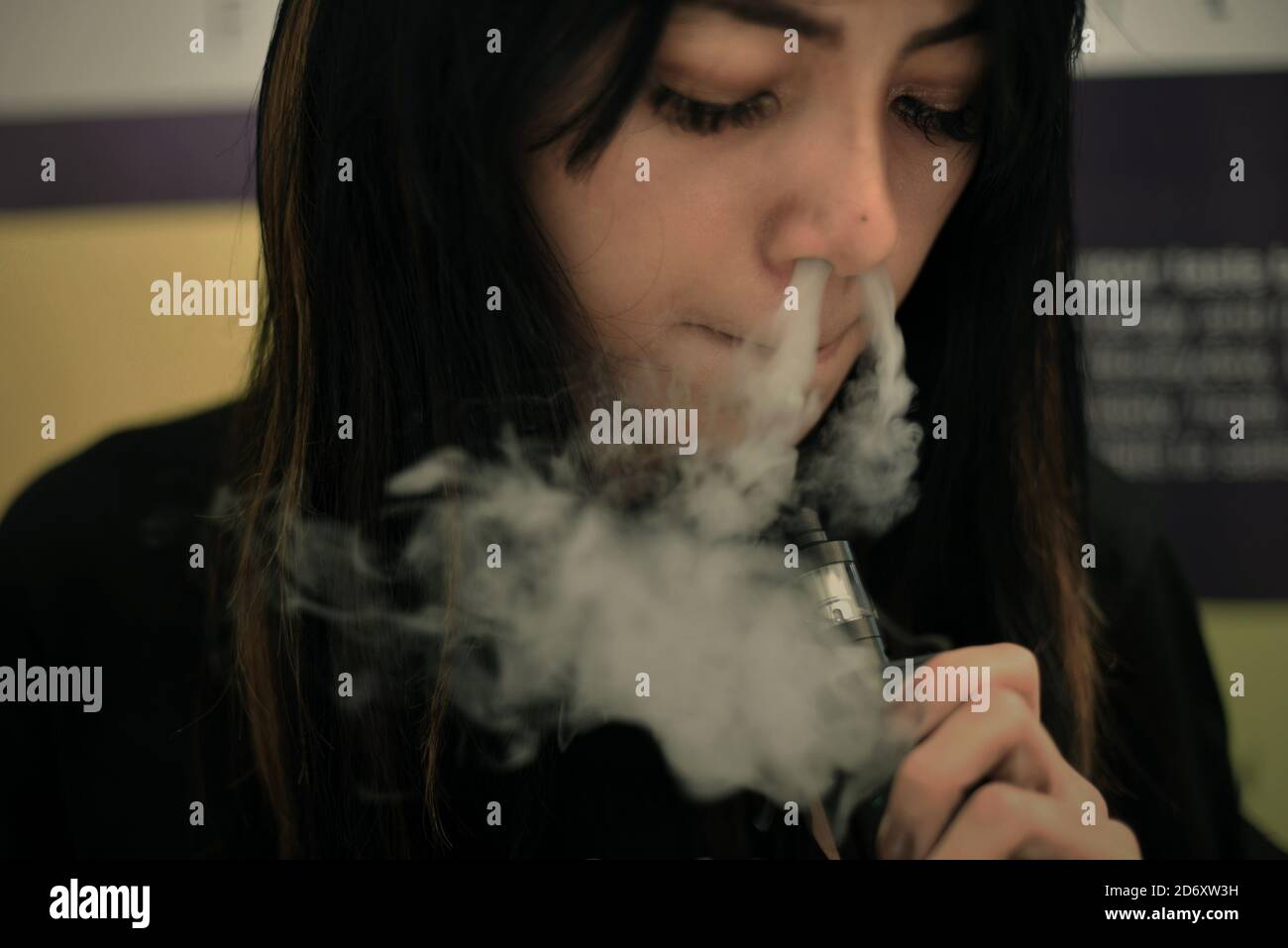 Silvia Arnisa exhala vapores para una fotografía mientras trabaja como promotora en el Jakarta VAPE Fest 2018 en Jakarta, Indonesia. Foto de stock