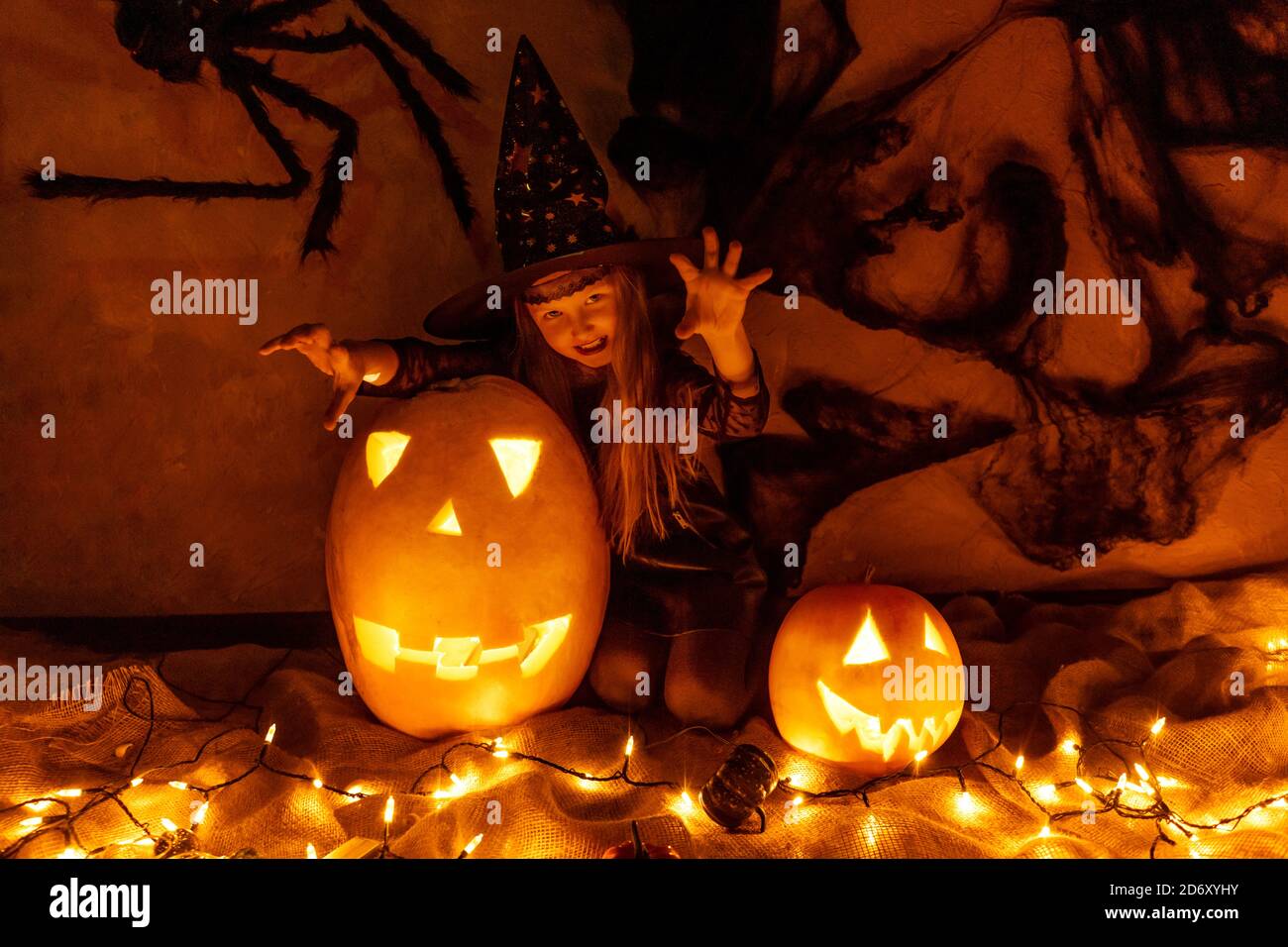 Chica que se divierte y celebra Halloween con traje de bruja. Garland,  calabazas linterna y tela en la pared como decoración Fotografía de stock -  Alamy