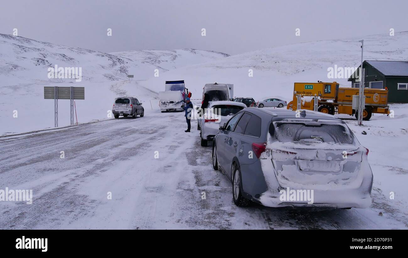 Skarsvåg, Noruega - 02/28/2019: Vehículos turísticos al inicio de la carretera al famoso Cabo Norte (Nordkapp) esperando el inicio del convoy. Foto de stock