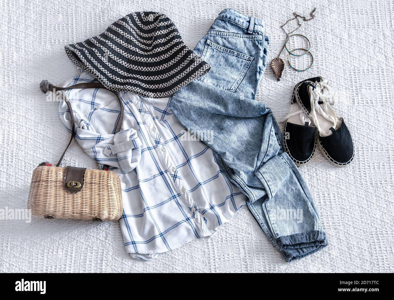 Conjunto con ropa de moda para mujer, camisa, jeans y bolsa con accesorios.  Sobre un fondo de tela ligera. Vista superior. Look moderno de cintura  baja. Lay plano Fotografía de stock -