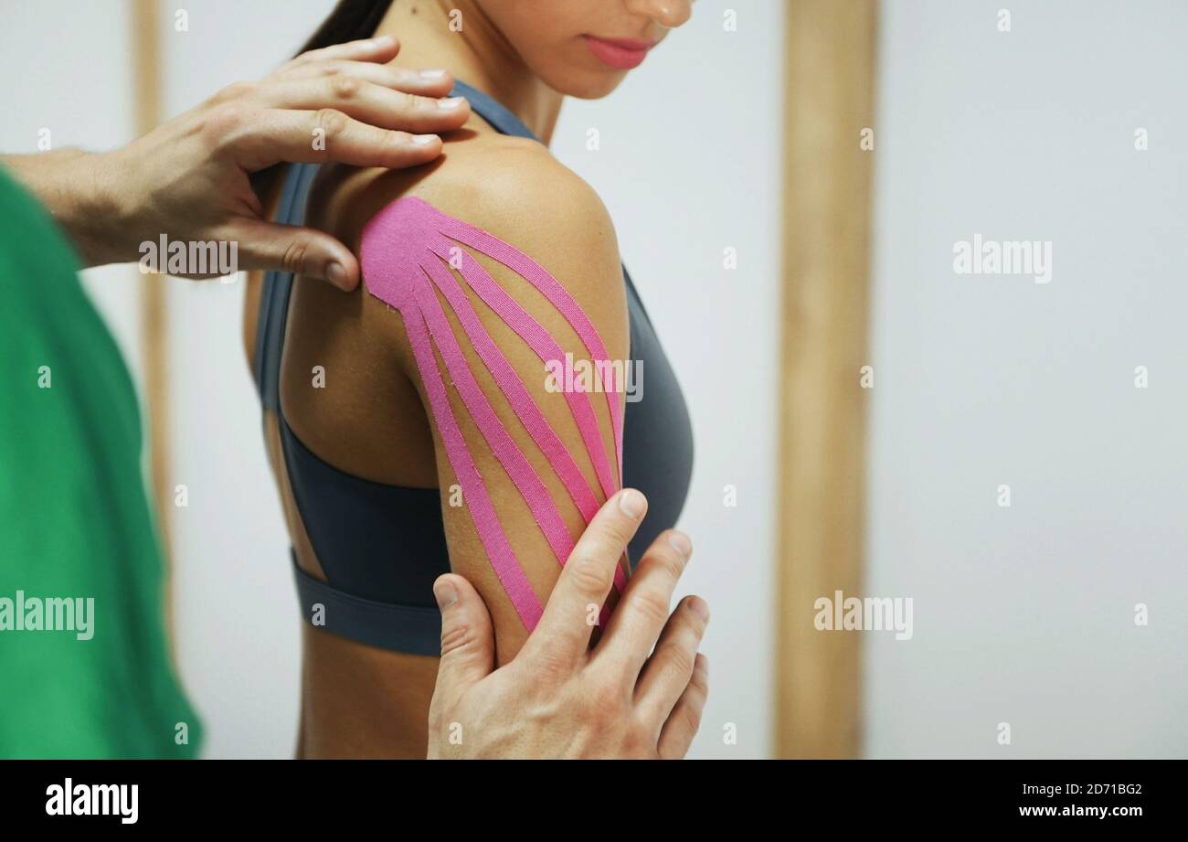 maratón Sin cabeza Corresponsal El médico ayuda a la mujer al tratamiento del hombro con cinta de cinesio  Fotografía de stock - Alamy