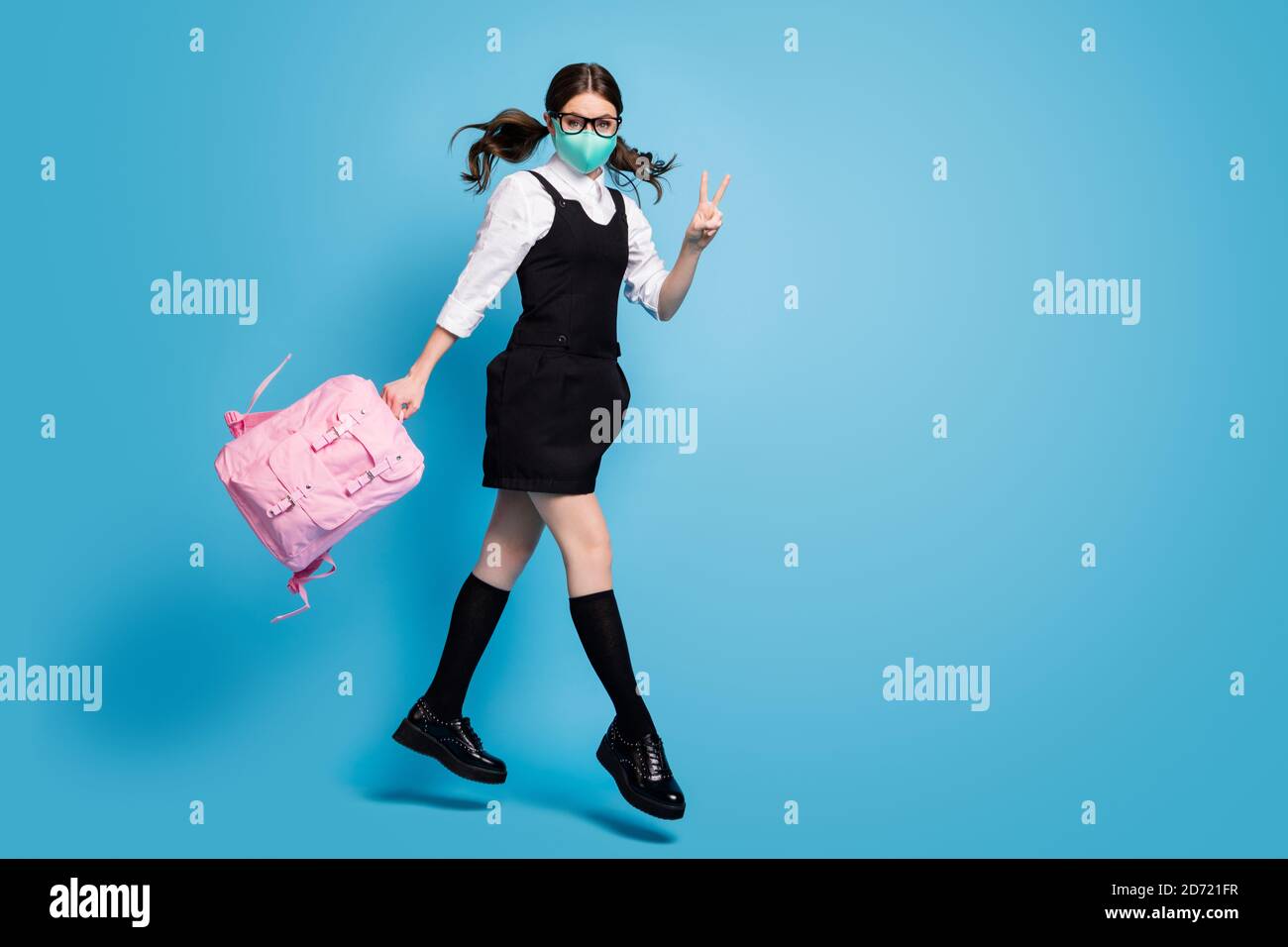 Foto de tamaño completo de la niña de la escuela secundaria de sueño saltar  sostener mochila mochila hacer v-signo usar blusa blanca vestido negro  falda general calcetines largos médico Fotografía de stock -