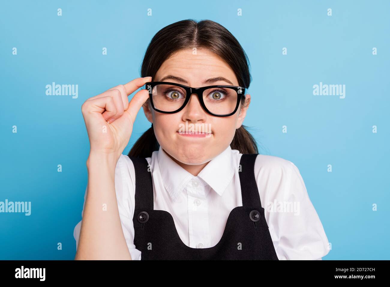 Foto de cerca de una niña de secundaria frustrada han estudiado problema no hacer tarea proyecto tocar manos gafas usar uniforme en general aislado sobre azul Foto de stock