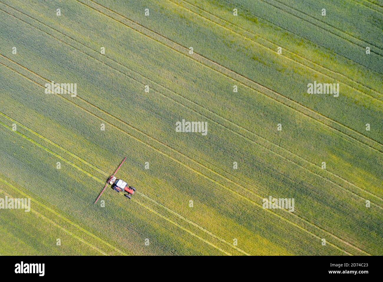 Drone punto de vista de un tractor pulverizando en un campo cultivado. Foto de stock