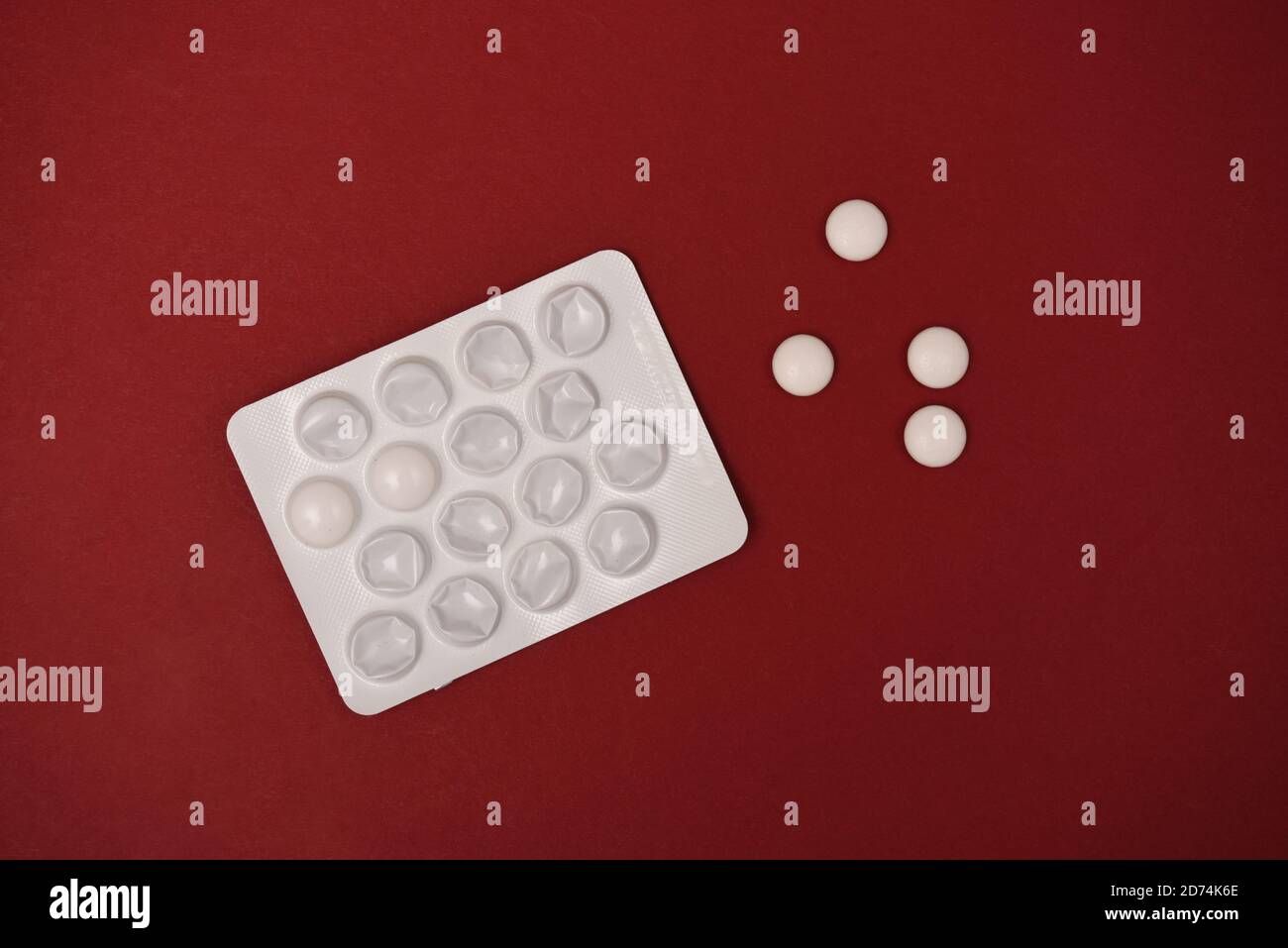 Envase de blíster de tabletas y pastillas sobre fondo rojo Foto de stock