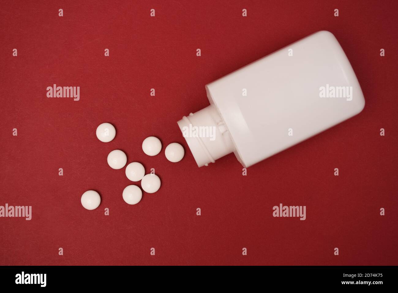 pastillas y una botella de pastillas aisladas sobre un fondo rojo Foto de stock