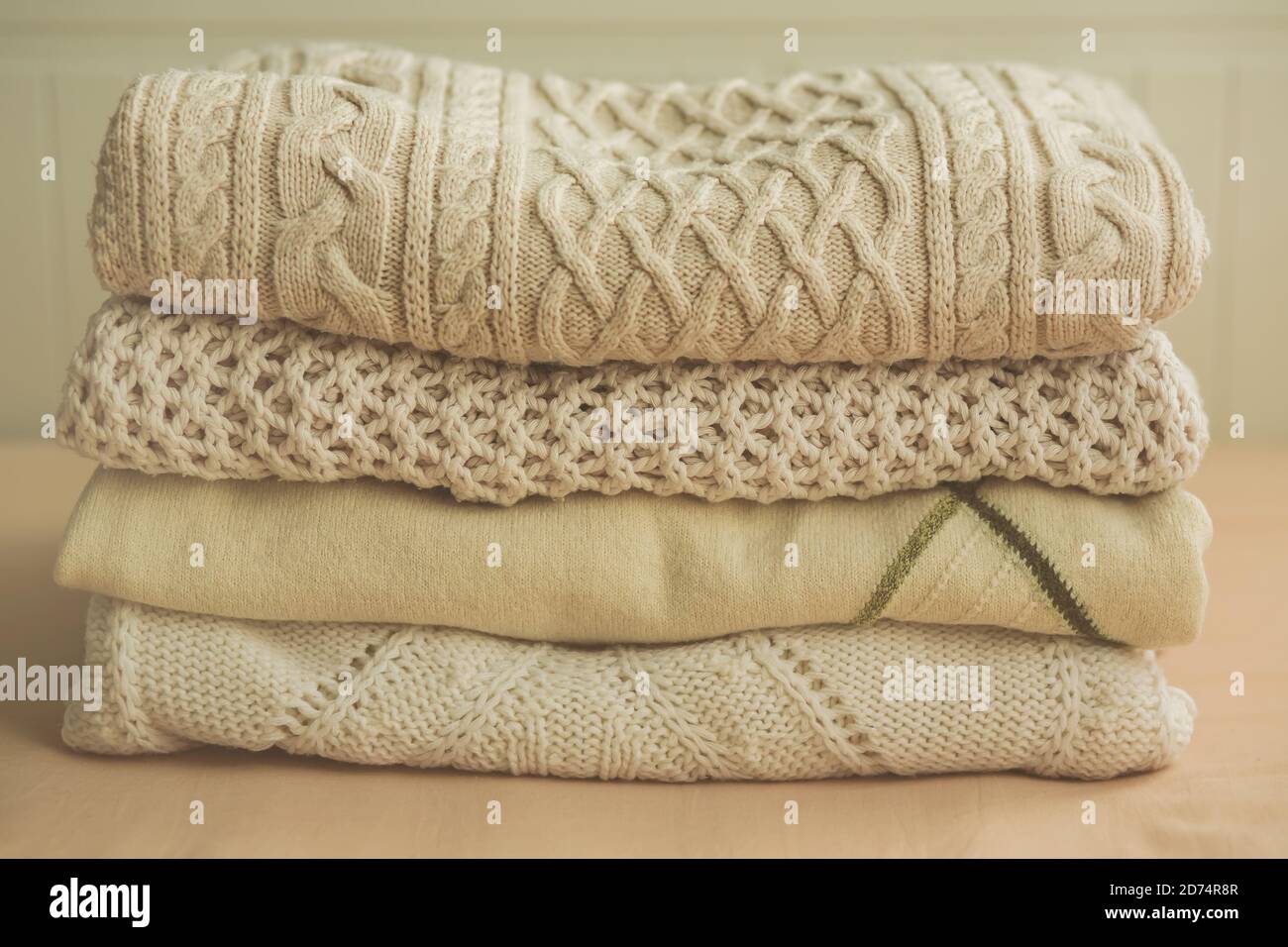 Cuatro suéteres tejidos blancos de lana se encuentran en un montón sobre un  fondo beige. Ropa para días fríos. La comodidad del hogar Fotografía de  stock - Alamy