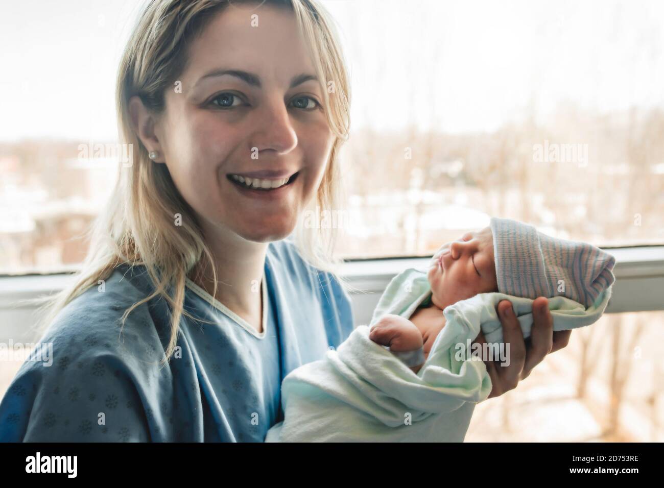 Madre con su bebé recién nacido en el hospital de enfrente de una ventana Foto de stock