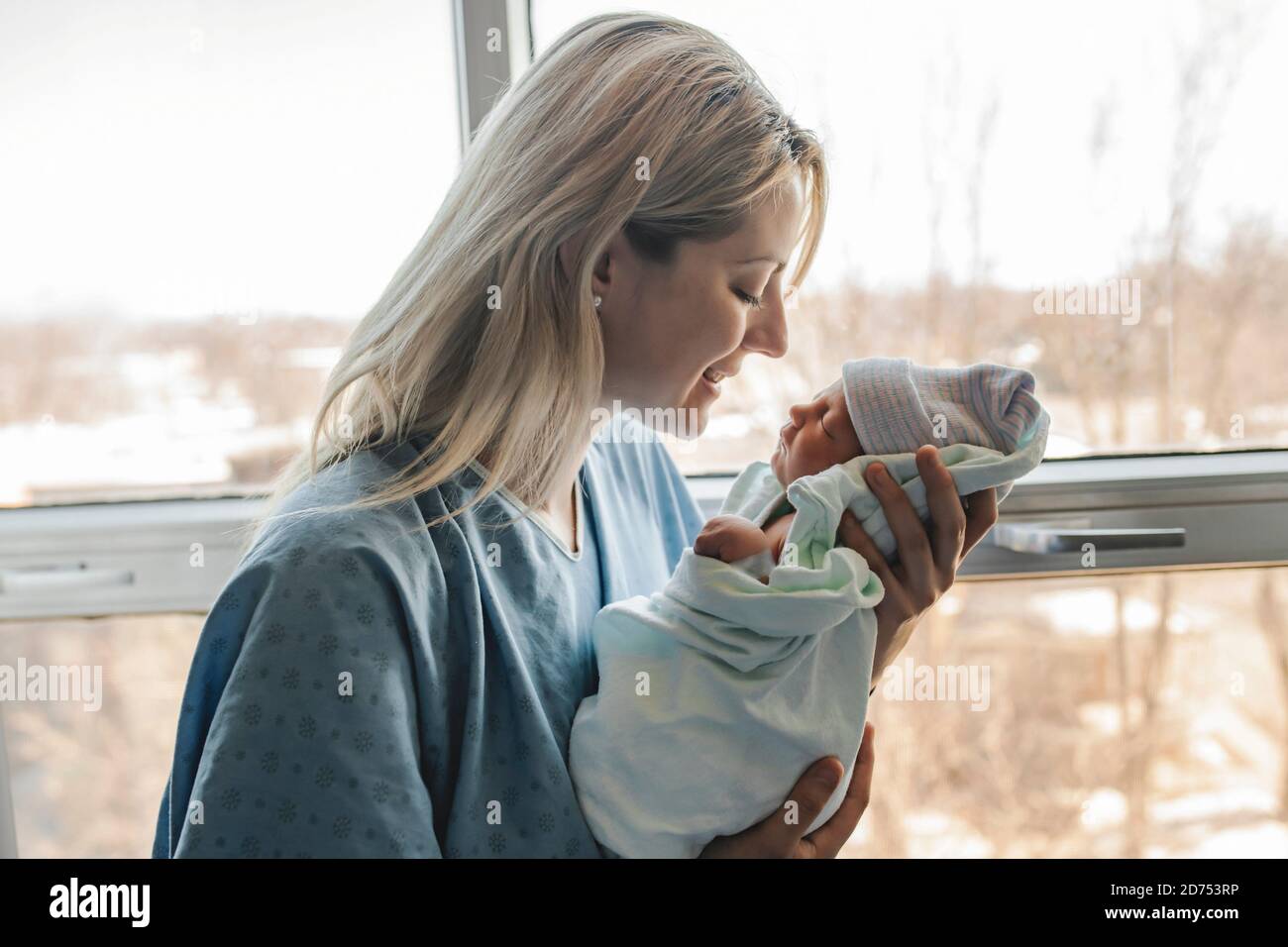 Madre con su bebé recién nacido en el hospital de enfrente de una ventana Foto de stock