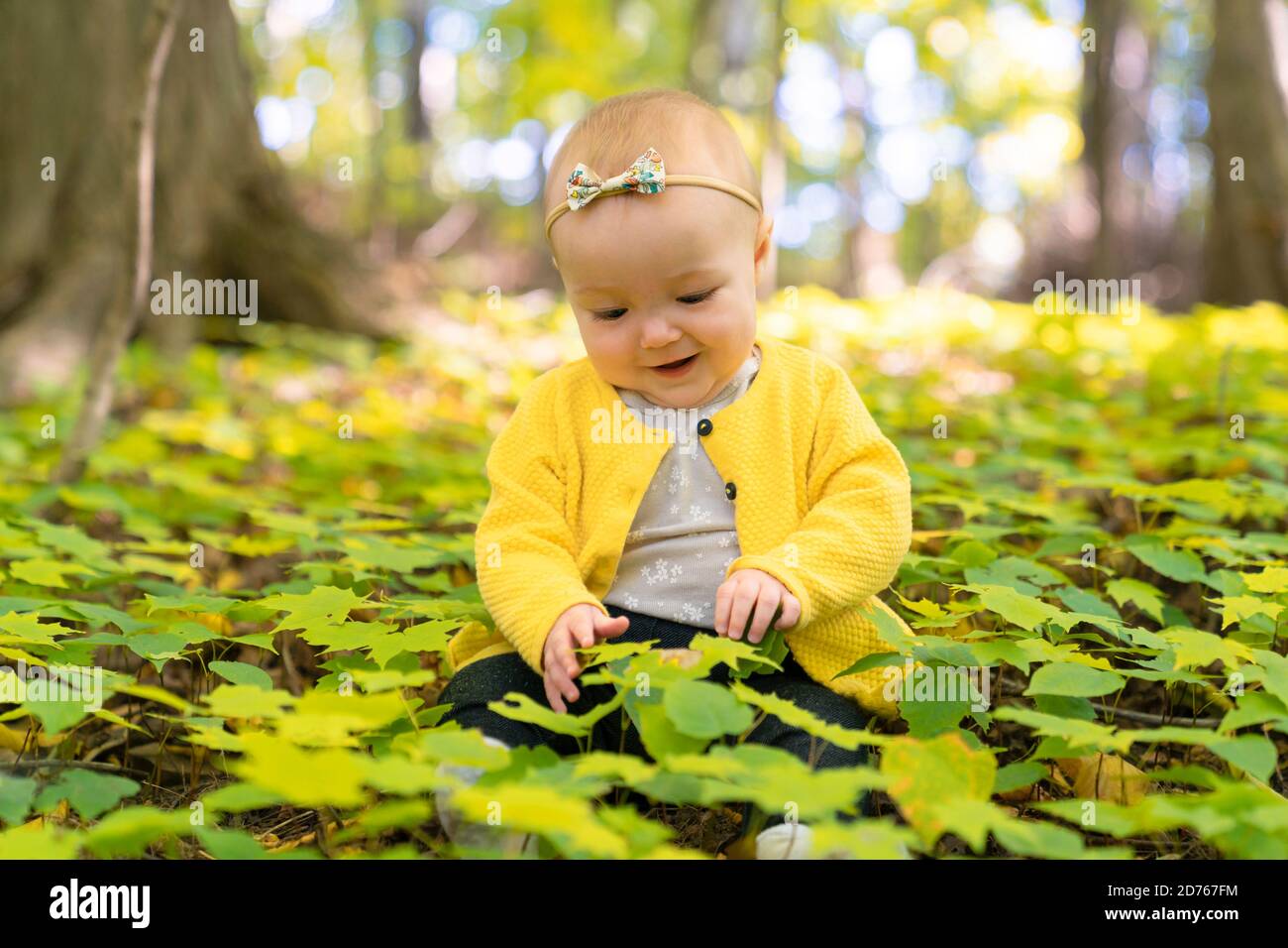 el bebé se sienta en el suelo en un bosque Foto de stock