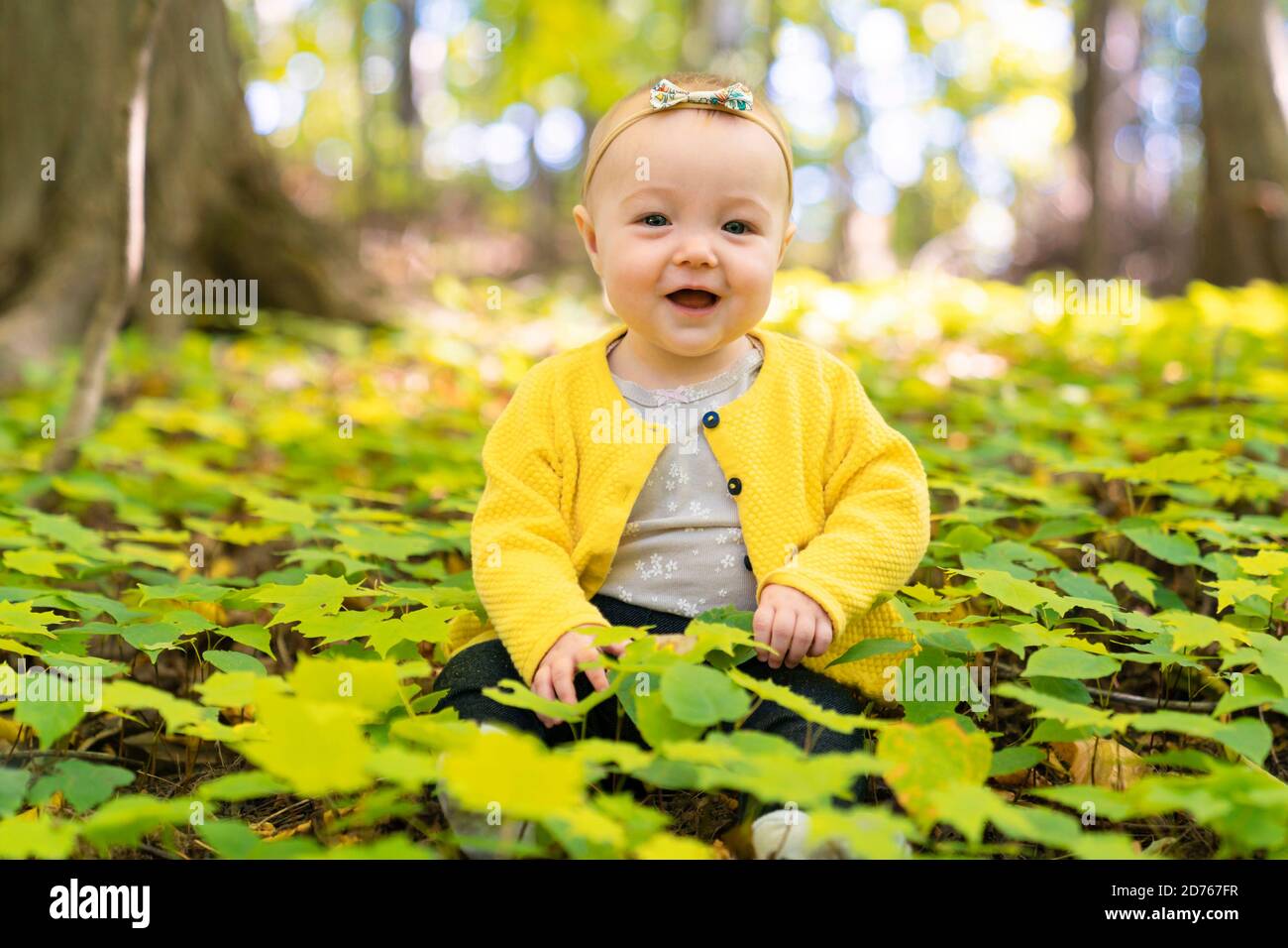 el bebé se sienta en el suelo en un bosque Foto de stock