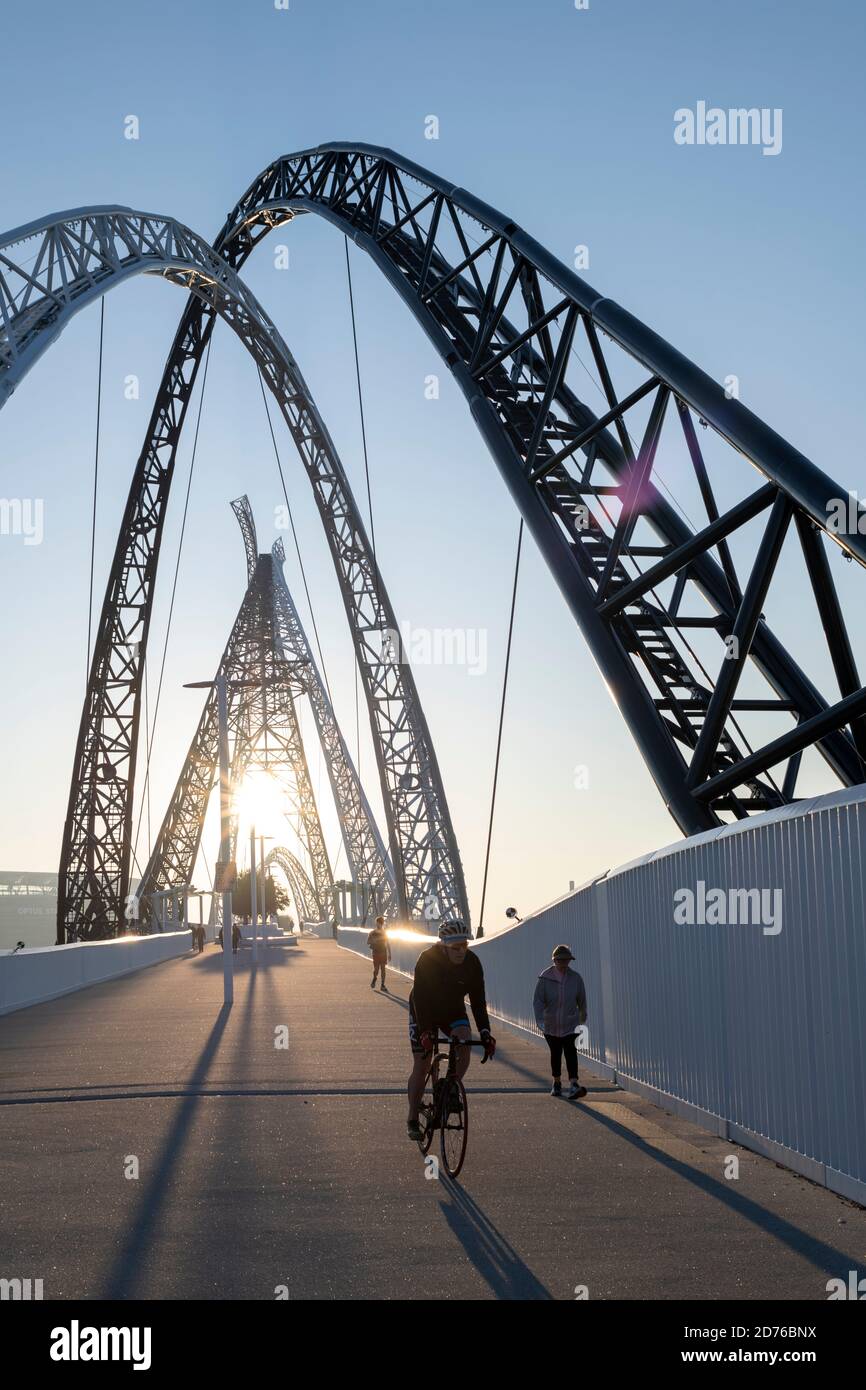 Ciclista y peatones en el puente Matagarup. Foto de stock