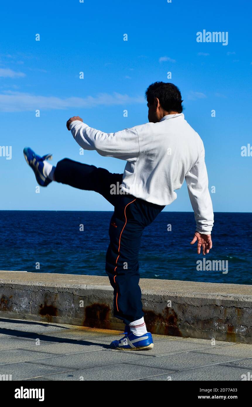 Hombre calentándose y estirando las piernas en el muelle. Foto de stock