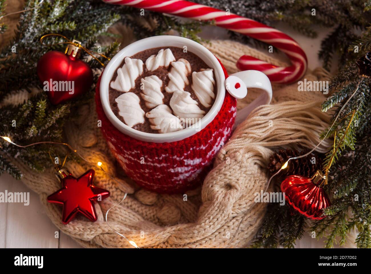 Taza de cacao caliente con malvaviscos en una caja roja de punto. Chocolate caliente sobre el fondo de la decoración de año Nuevo Foto de stock