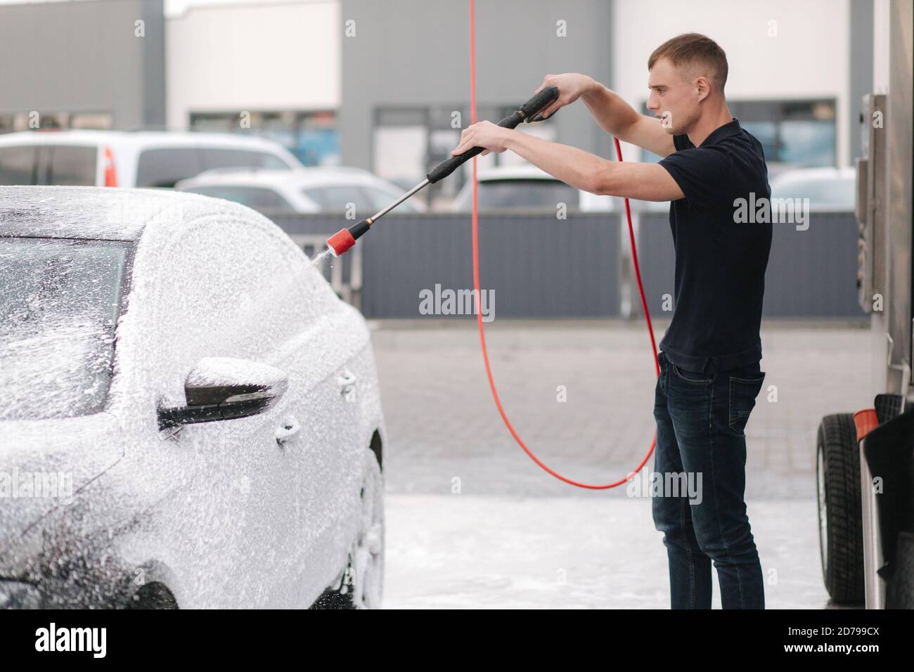 Limpieza del coche con espuma activa. Hombre lavando su coche en