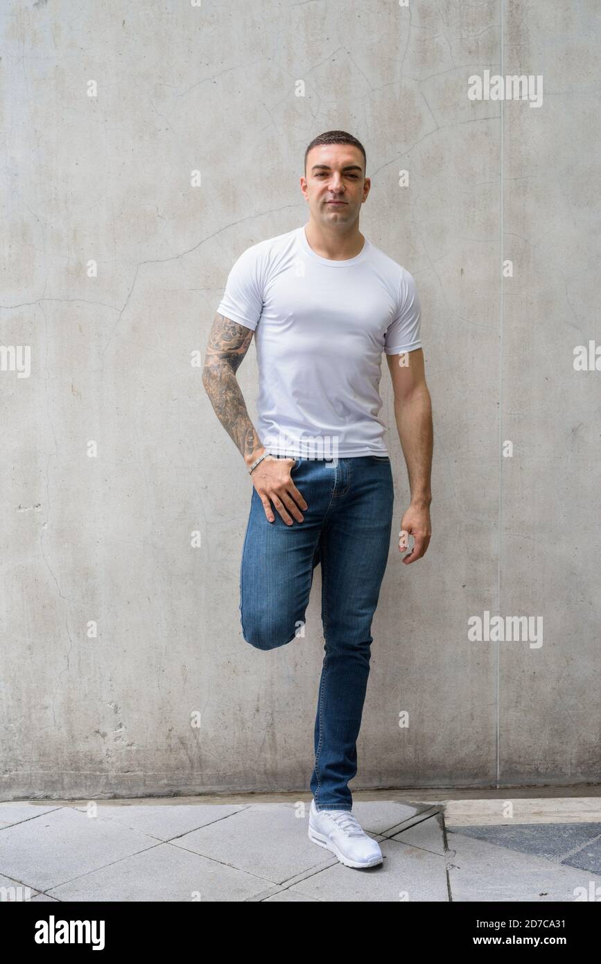 Tiro de cuerpo entero de hombre guapo con tatuajes inclinados pared  Fotografía de stock - Alamy