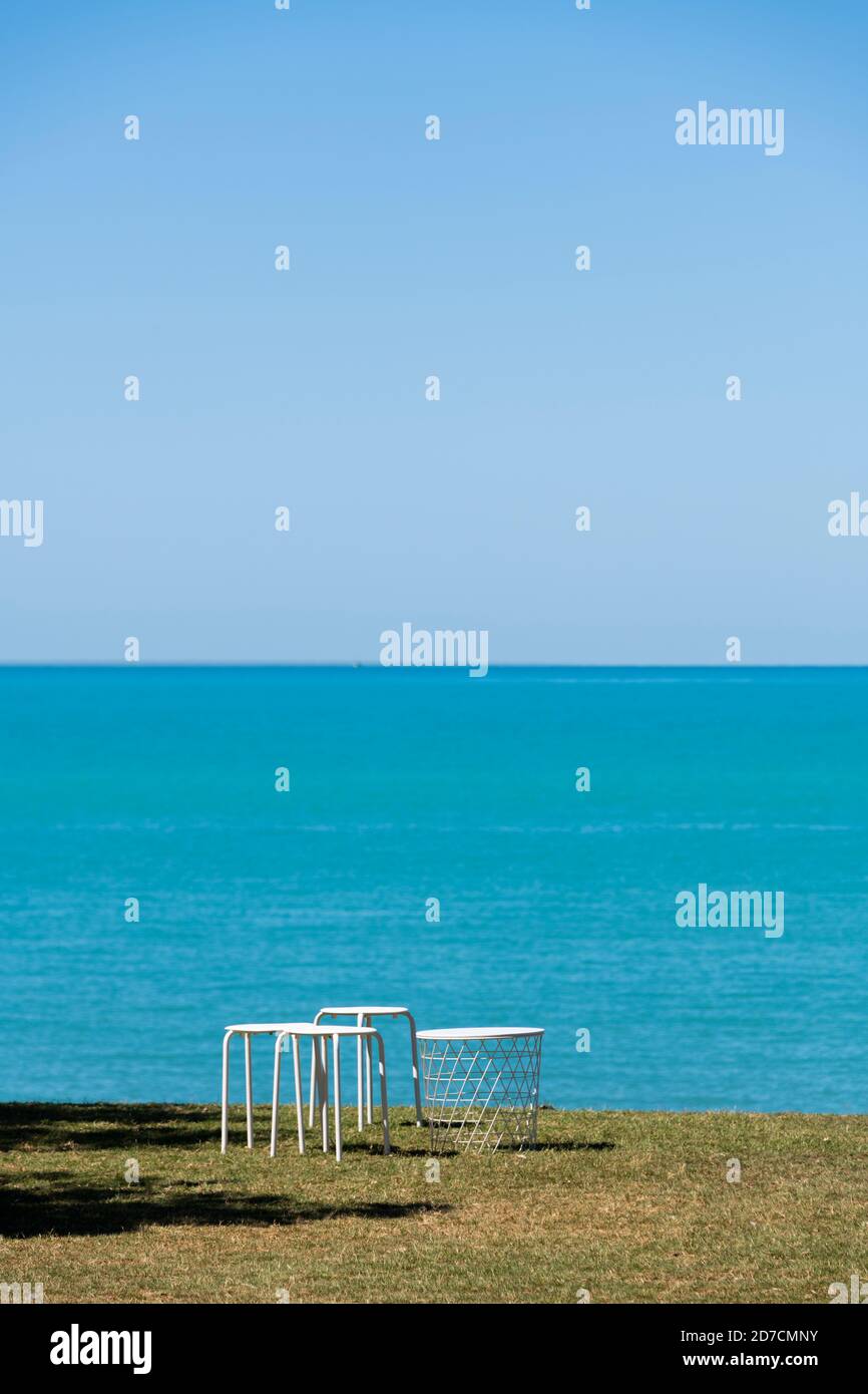 Mesa y taburetes sobre hierba por encima de la playa de la ciudad. Foto de stock