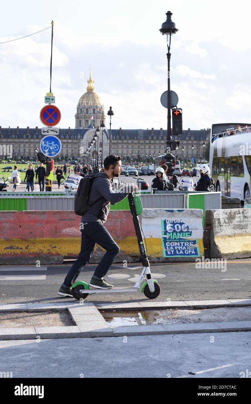 Estilo de vida de un hombre con mochila de conducción scooter eléctrico en el sendero frente a Les Invalides en el 7º arrondissement de París, Francia Foto de stock