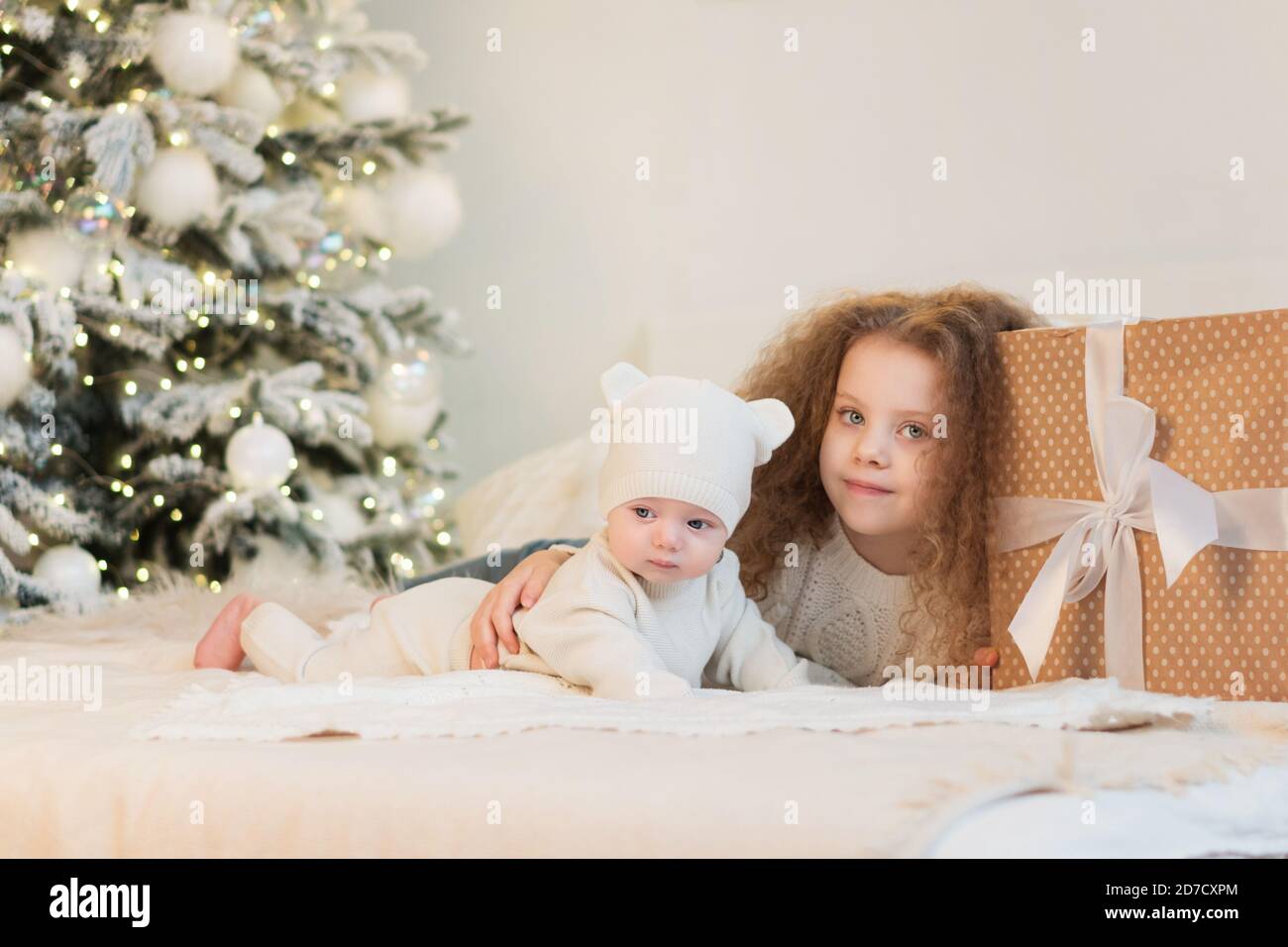 Niños alegres del yute que tienen diversión cerca del árbol. Familia  amorosa con regalos en la habitación. Nochebuena en casa. Mañana de  Navidad. Feliz Navidad y felices fiestas Fotografía de stock -