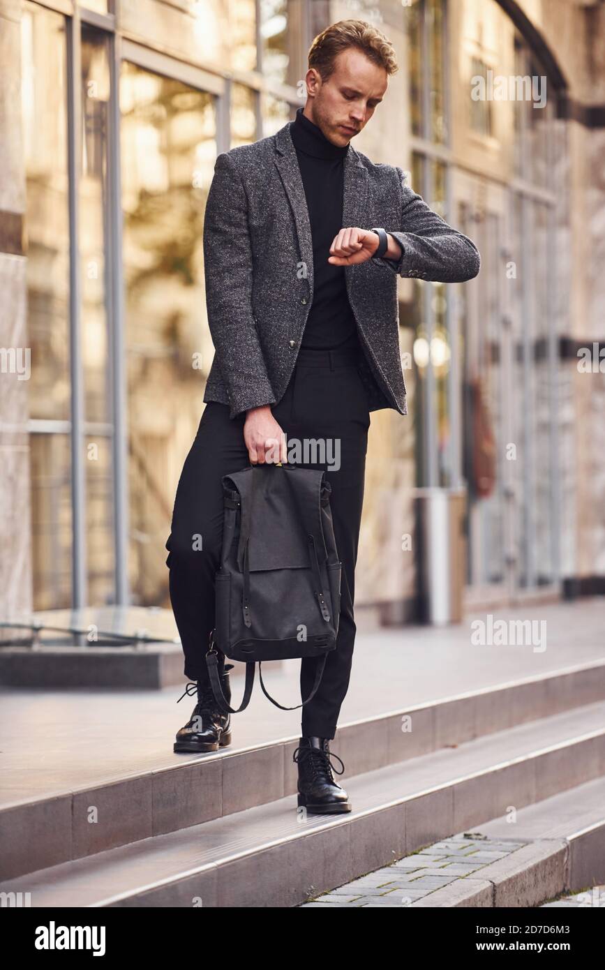 Hombre con elegante ropa formal y con bolsa está fuera contra el edificio  moderno Fotografía de stock - Alamy