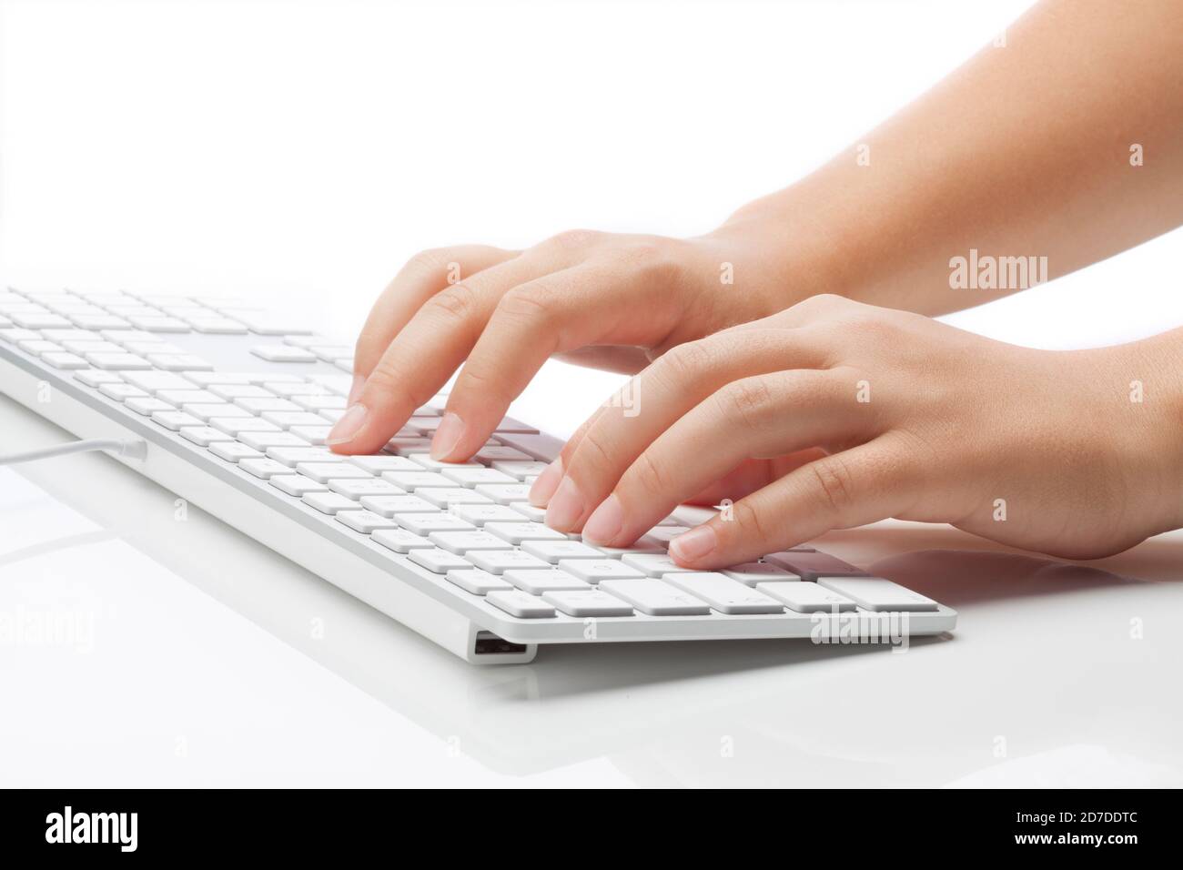 Mujer joven escribiendo en el teclado. Luz suave sobre fondo blanco Foto de stock
