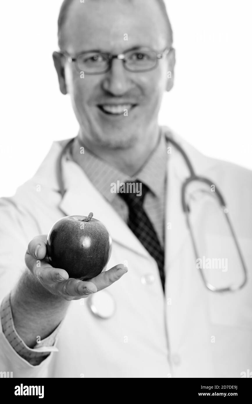 Foto de estudio de un médico hombre feliz sonriendo mientras daba manzana con enfoque en la manzana Foto de stock