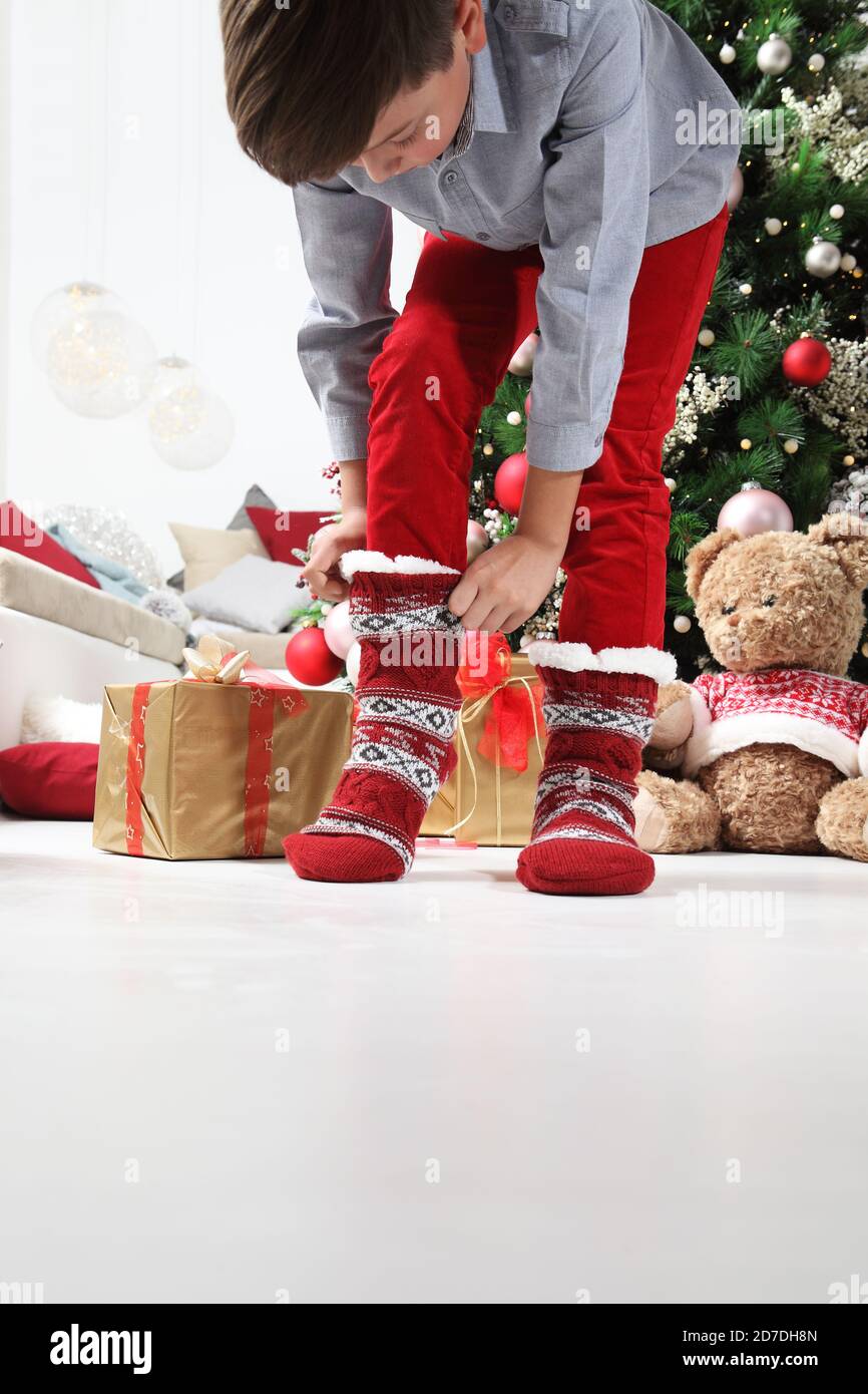 feliz Navidad, el niño lleva calcetines de Navidad cerca árbol y paquetes de regalo de peluche Fotografía de - Alamy