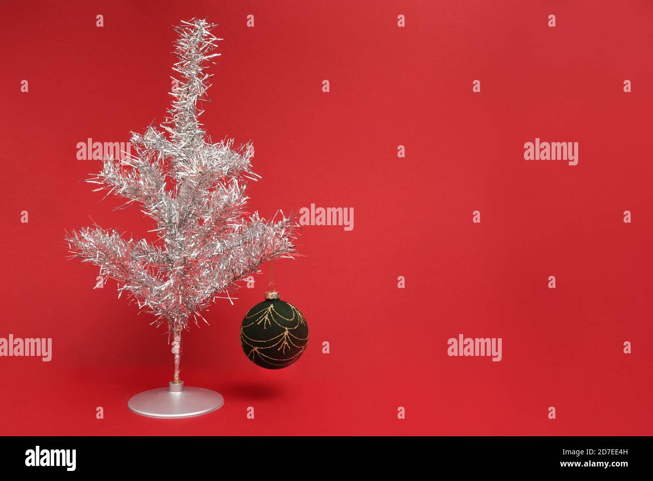 Árbol de Navidad de tinsel retro encendido con bola en un rojo antecedentes Foto de stock
