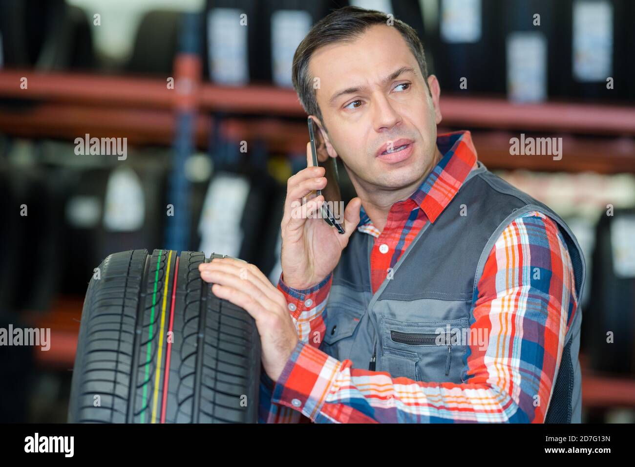 mecánico sosteniendo el neumático y hablando por teléfono Fotografía de  stock - Alamy