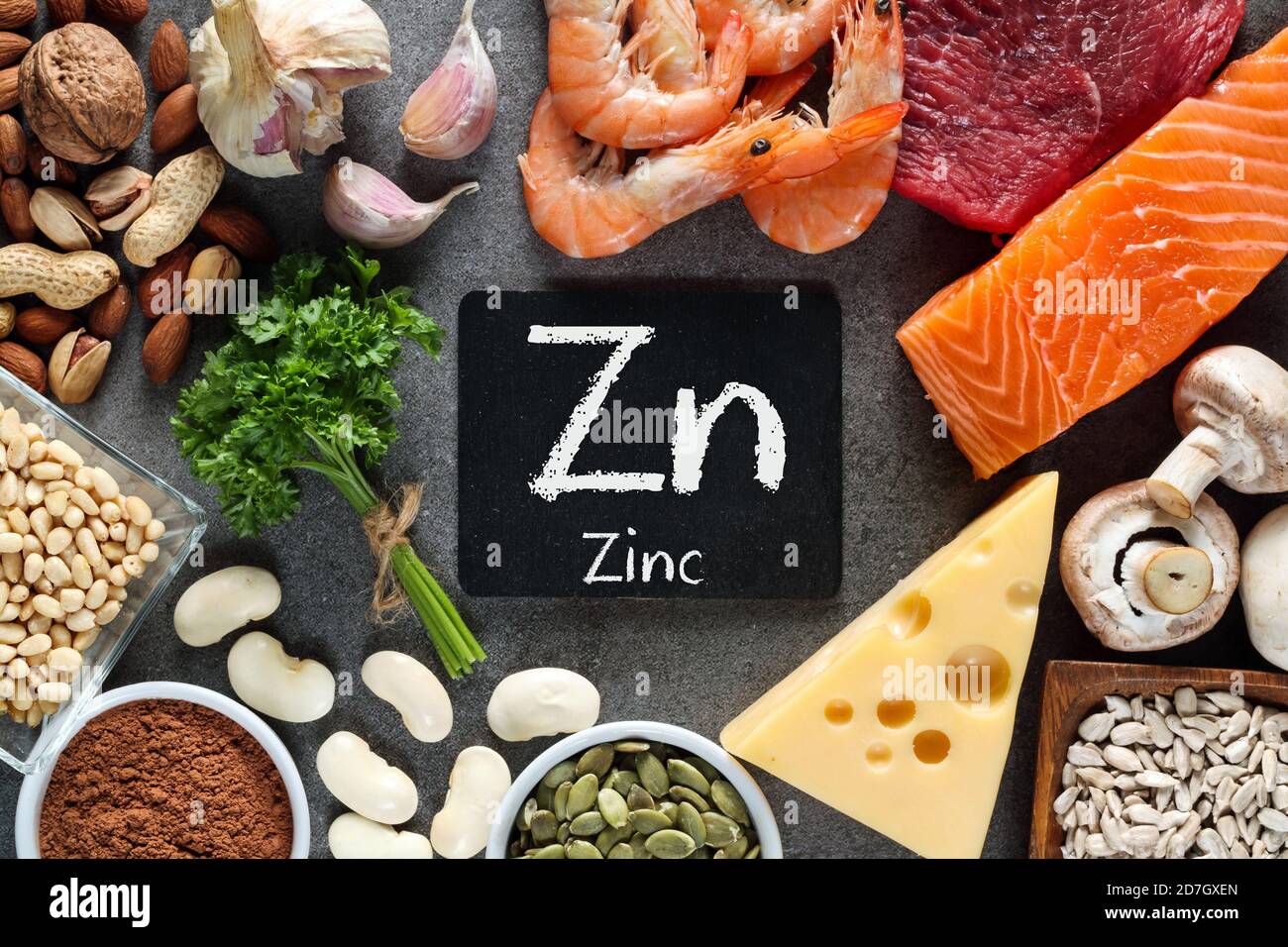 Alimentos ricos en zinc como salmón, mariscos-camarones, carne de res, queso amarillo, hojas de perejil, setas, cacao, semillas de calabaza, ajo, frijol, almendras, nuez de pino. Foto de stock
