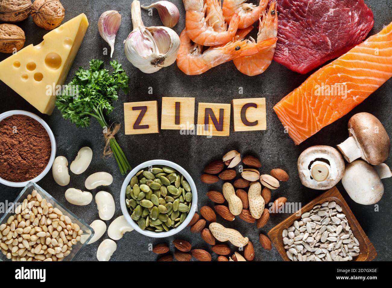 Alimentos ricos en zinc como salmón, mariscos-camarones, carne de res, queso amarillo, hojas de perejil, setas, cacao, semillas de calabaza, ajo, frijol, almendras, nuez de pino. Foto de stock