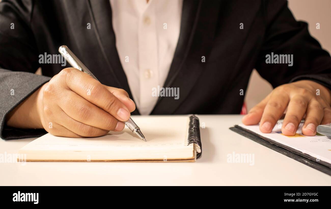 Primeros planos de un hombre que escribió un cuaderno espiral sobre la mesa con una taza de café y la idea del escritor. Foto de stock