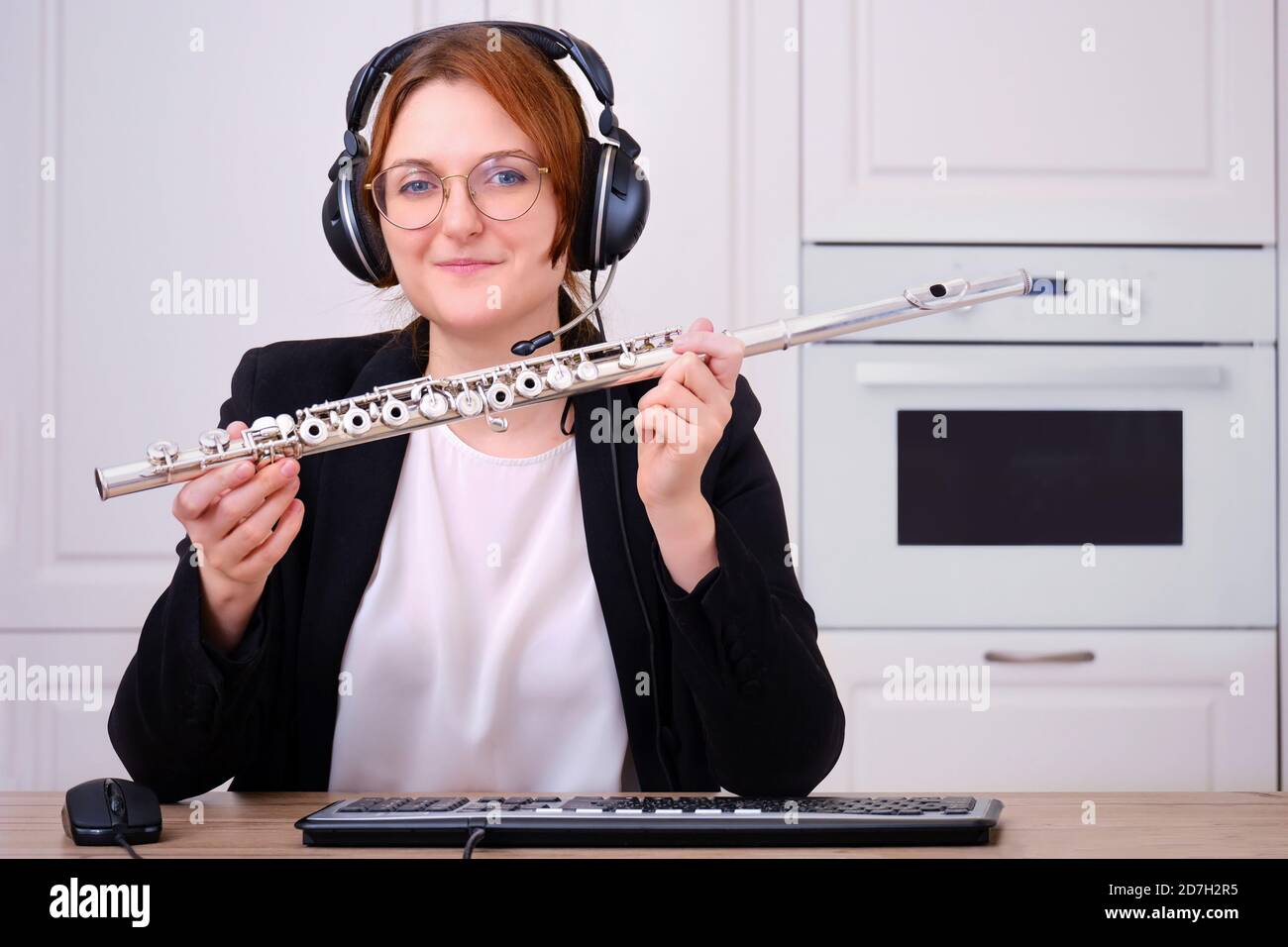 Un profesor de música proporciona formación en línea para tocar la flauta.  Una flautista femenina enseña una lección de flauta a través de Internet,  vista de cámara. Concepto en línea Fotografía de