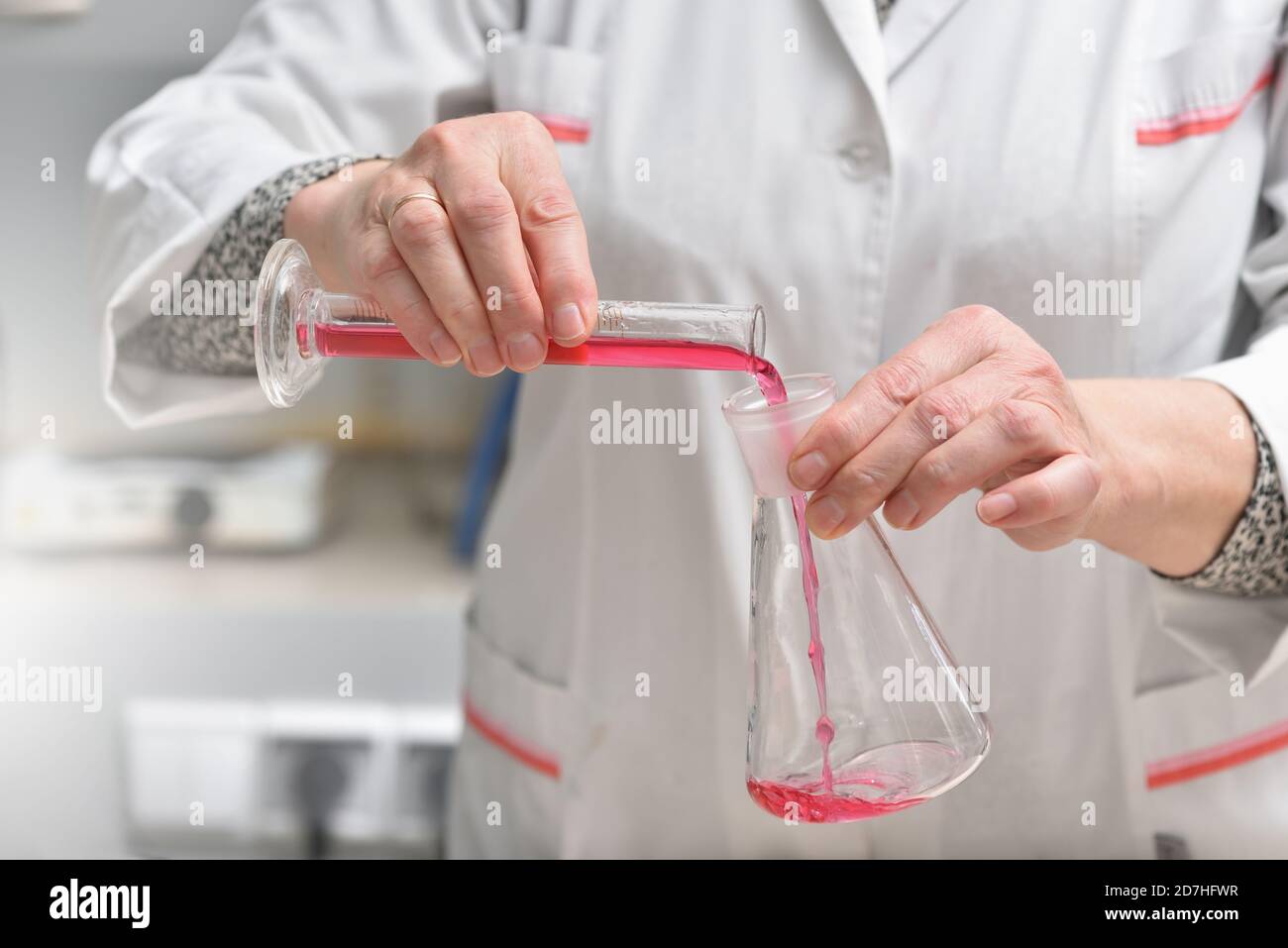 el asistente de laboratorio vierte el líquido en un primer plano del tubo de ensayo Foto de stock