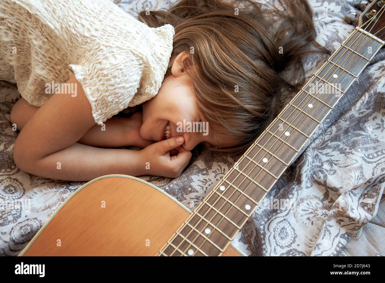 Niña soñadora acostada con su guitarra acústica - Cute niña con los ojos  cerrados sonriendo con la mano en el Cara - el sueño es ser un guitarrista  Fotografía de stock - Alamy