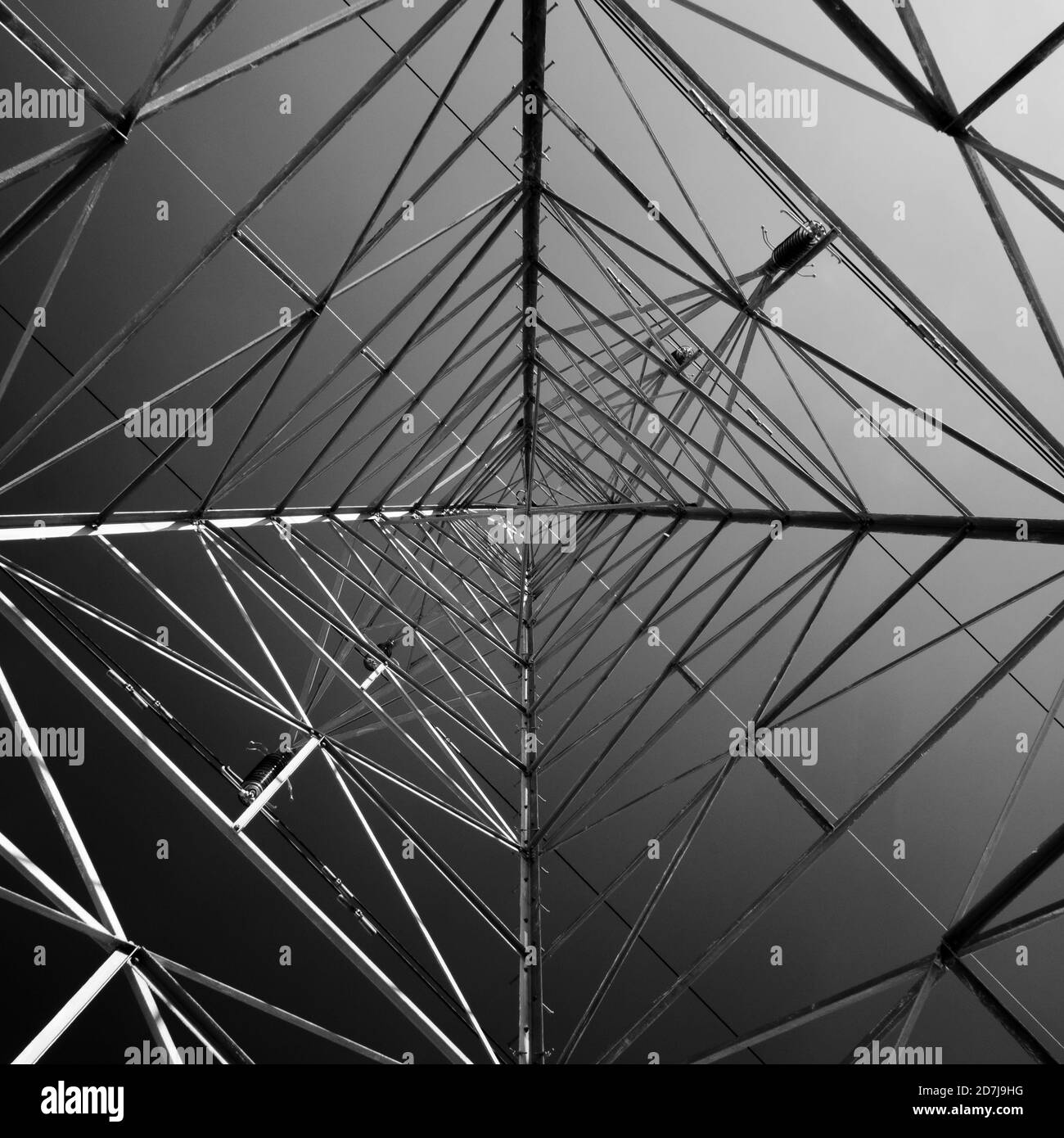 Una vista abstracta en blanco y negro mirando a un pilón de electricidad de alta tensión. Foto de stock