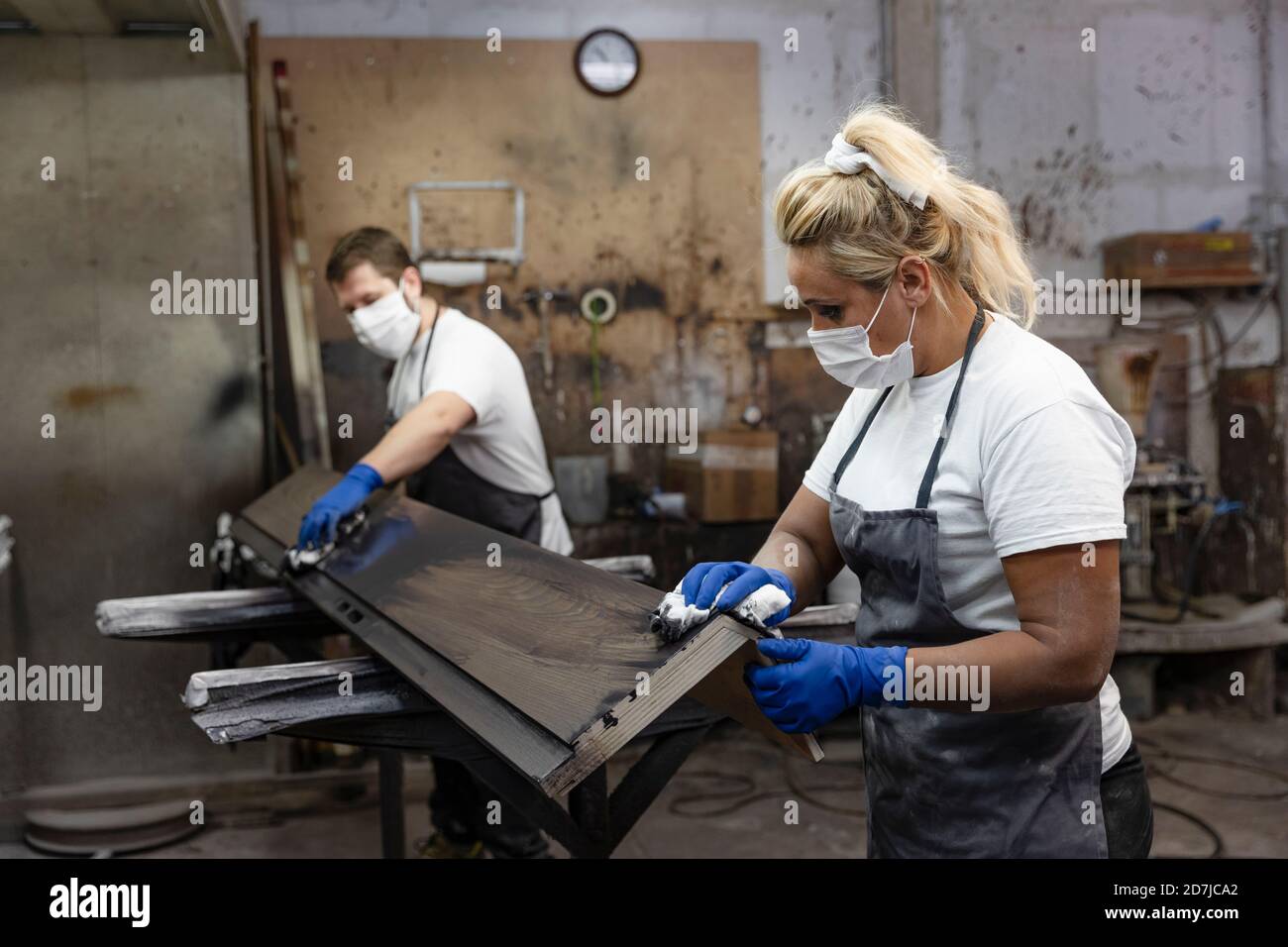 Carpinteros que aplican barniz sobre madera con tela mientras están de pie  fábrica Fotografía de stock - Alamy