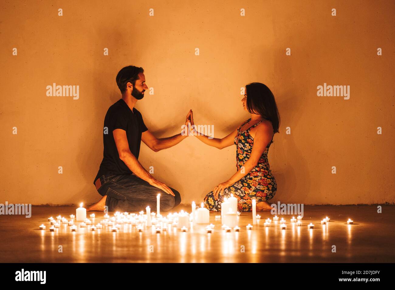 Pareja tocando las manos mientras se arrodilla con velas encendidas en el  cuarto oscuro en casa Fotografía de stock - Alamy