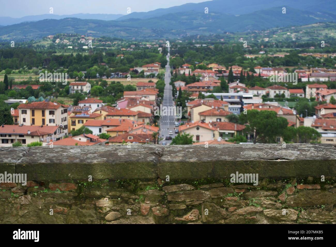 Un tramo de las antiguas murallas defensivas de la ciudad de Arezzo. Una carretera asfaltada recta y parte de la ciudad moderna en el fondo Foto de stock