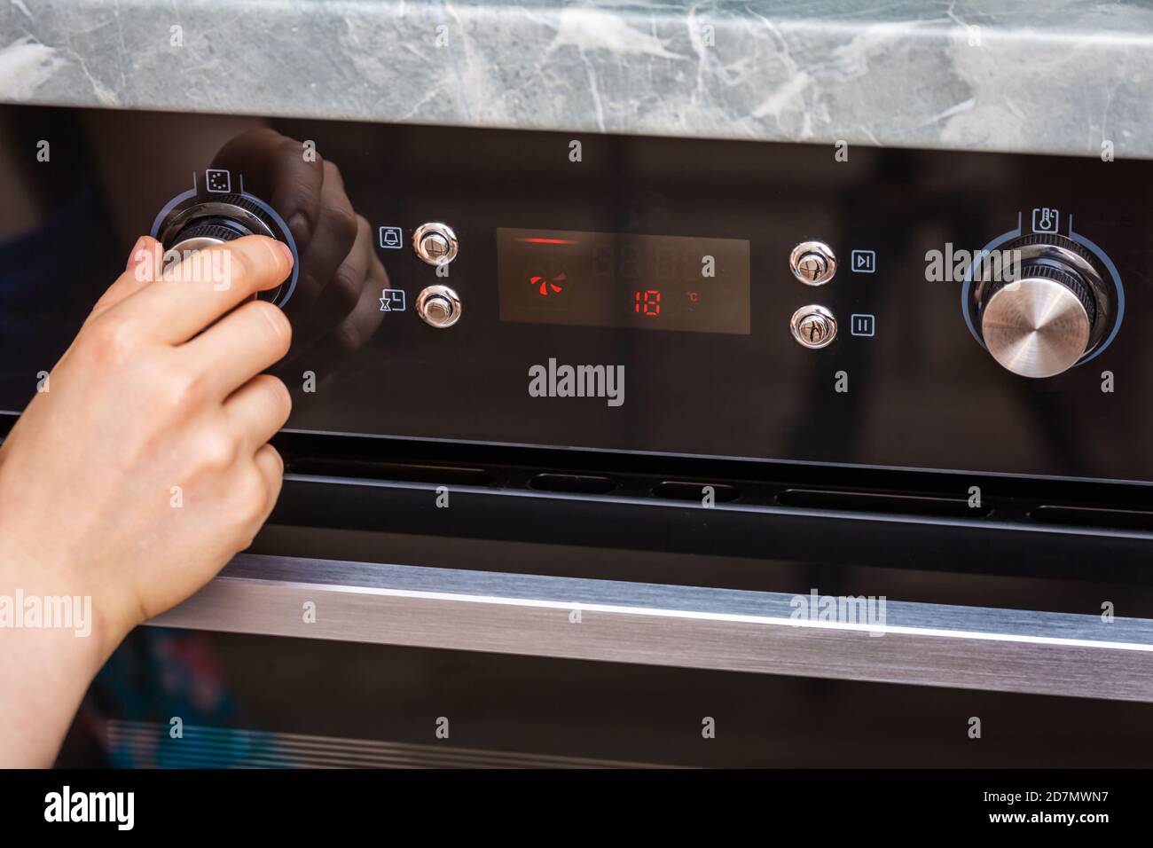 La mano femenina enciende el horno para hacer un pastel en casa. Primer  plano del mando del horno. Vista del horno eléctrico negro, mando con un  icono de aire caliente. El conc