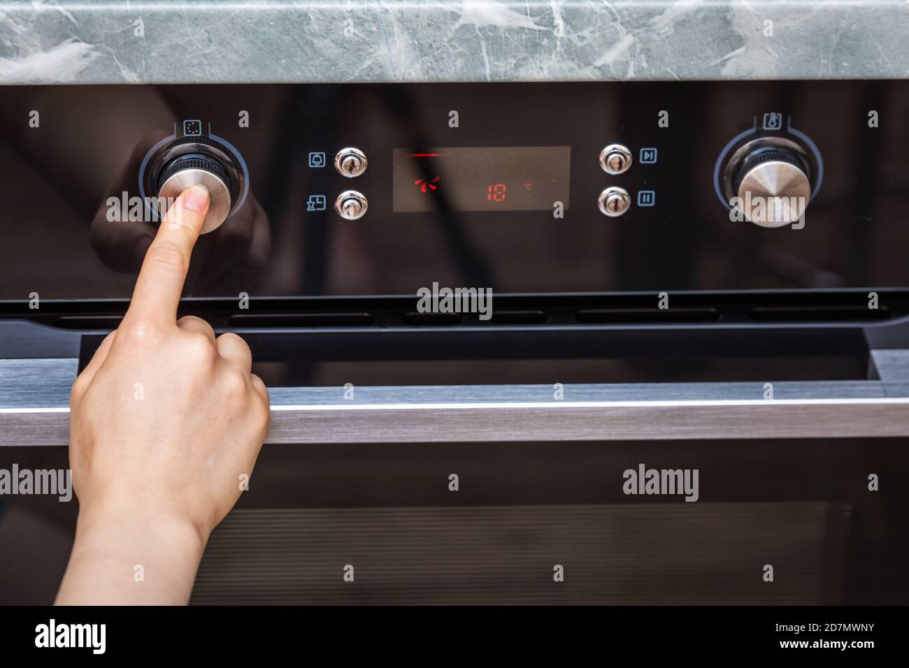 La mano femenina enciende el horno para hacer un pastel en casa. Primer  plano del mando del horno. Vista del horno eléctrico negro, mando con un  icono de aire caliente. El conc