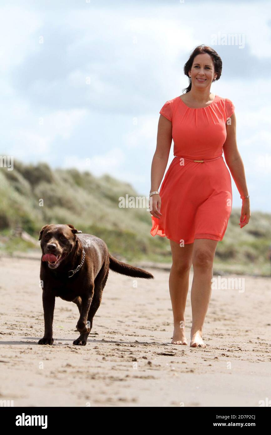Las mujeres blancas y atractivas del cáucaso desnudas caminan a lo largo de  la playa escocesa Y remar con perros de mascotas mientras hablan de  mediados de los 40 Fotografía de stock -