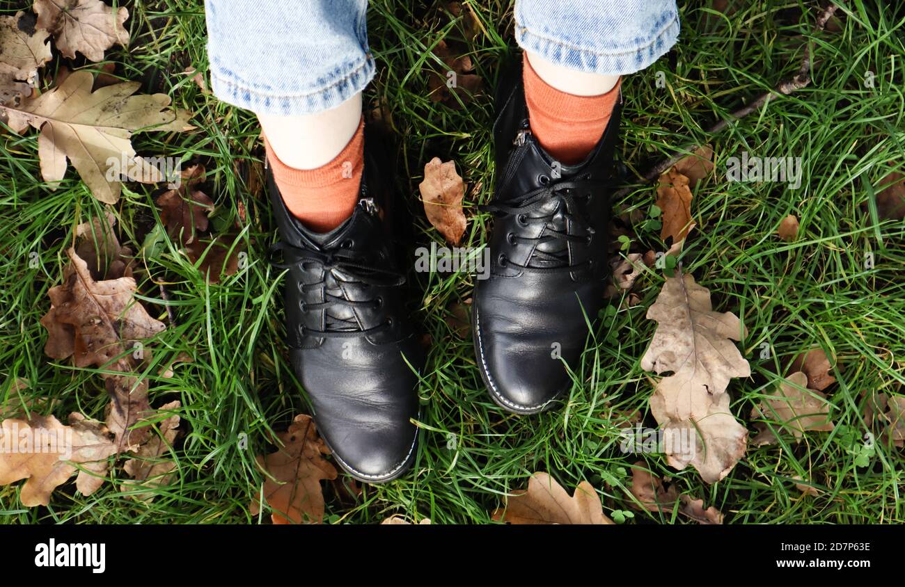 Patas femeninas en botas negras sobre hierba verde con hojas otoñales  amarillas caídas en el parque. Concepto de otoño. Zapatillas para mujer en  el follaje otoñal Fotografía de stock - Alamy