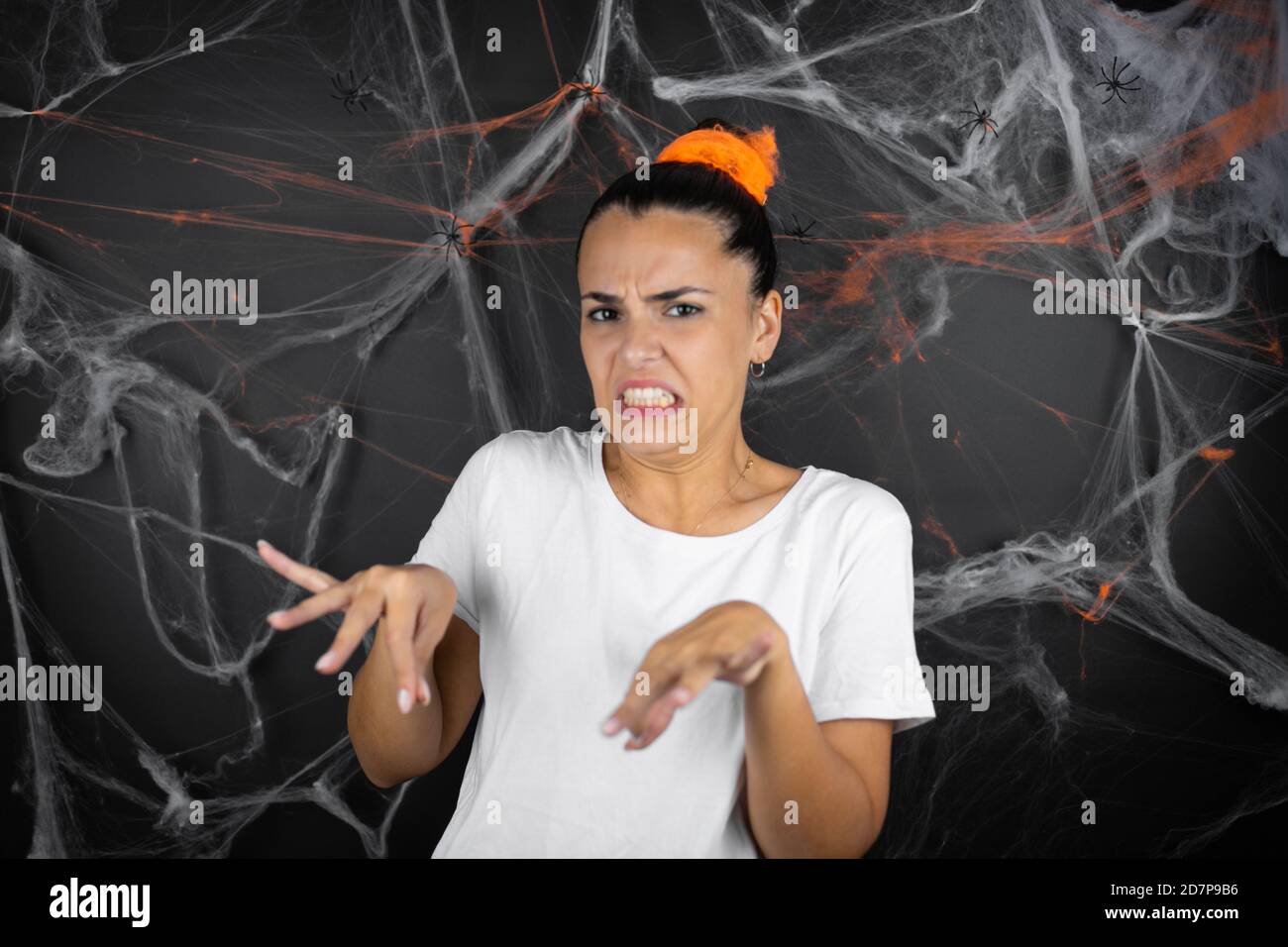 Joven hermosa mujer sobre fondo negro con telarañas y la expresión disgustada, disgustada y temerosa haciendo cara de disgusto porque aversión Foto de stock