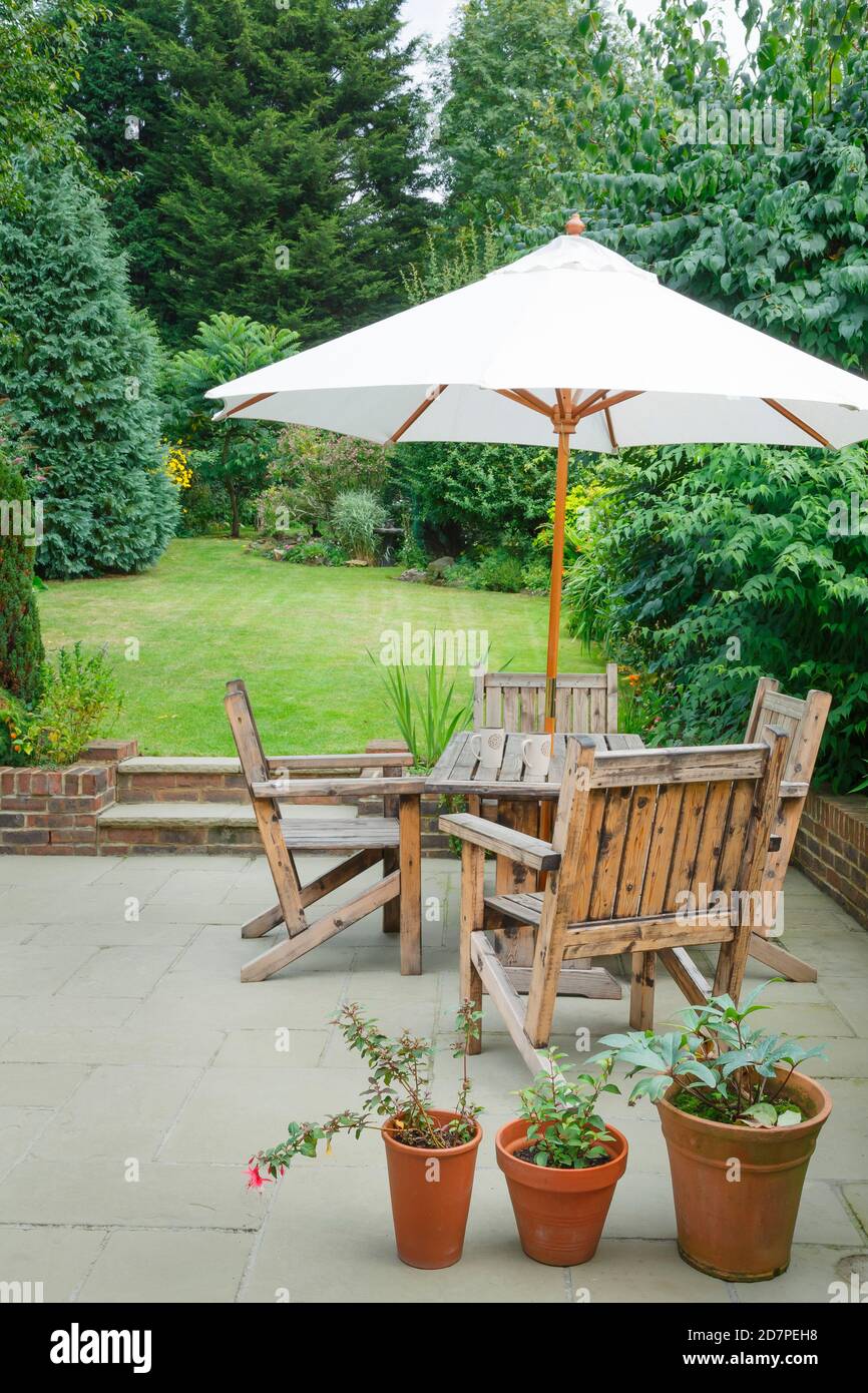 Jardín trasero suburbano británico en verano con patio, muebles de jardín de  madera y una sombrilla o sombrilla Fotografía de stock - Alamy