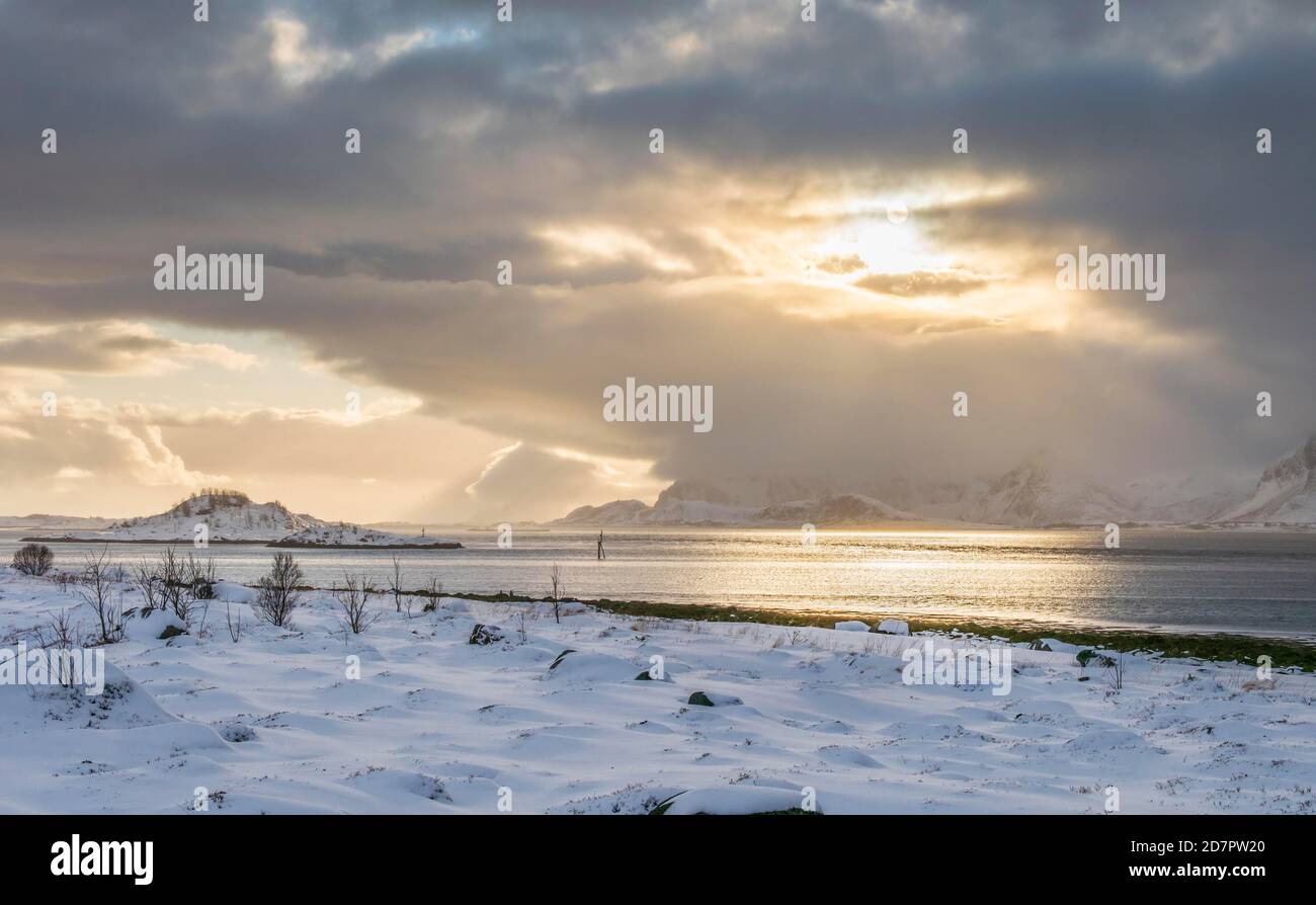Paisaje nevado en el mar y fiordo, atmósfera de nubes, luz solar cálida, Nordland, Lofoten, Noruega Foto de stock