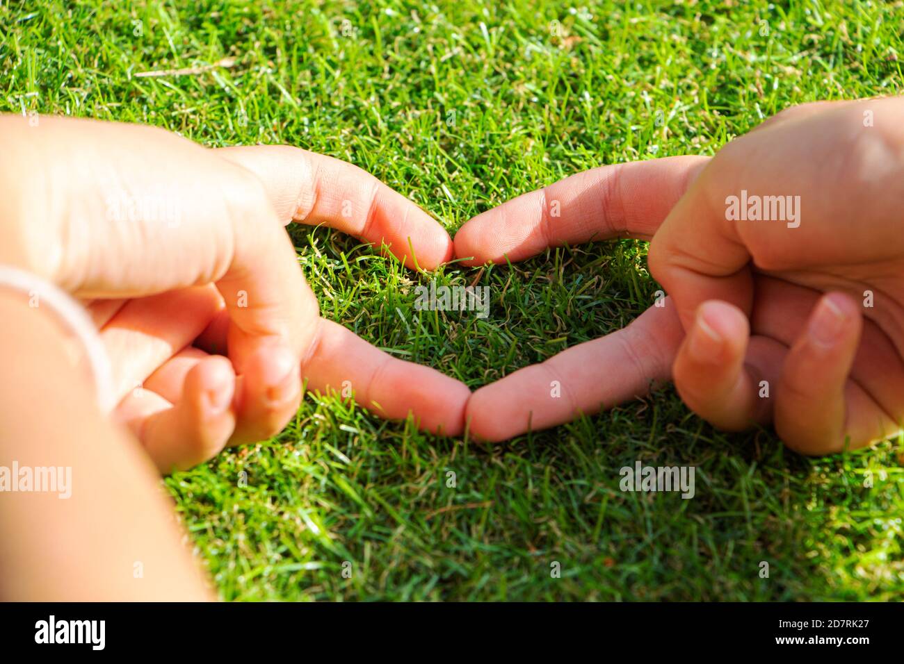 la mano en forma de corazón de una mujer toca la hierba. el césped  artificial no es hierba real Fotografía de stock - Alamy