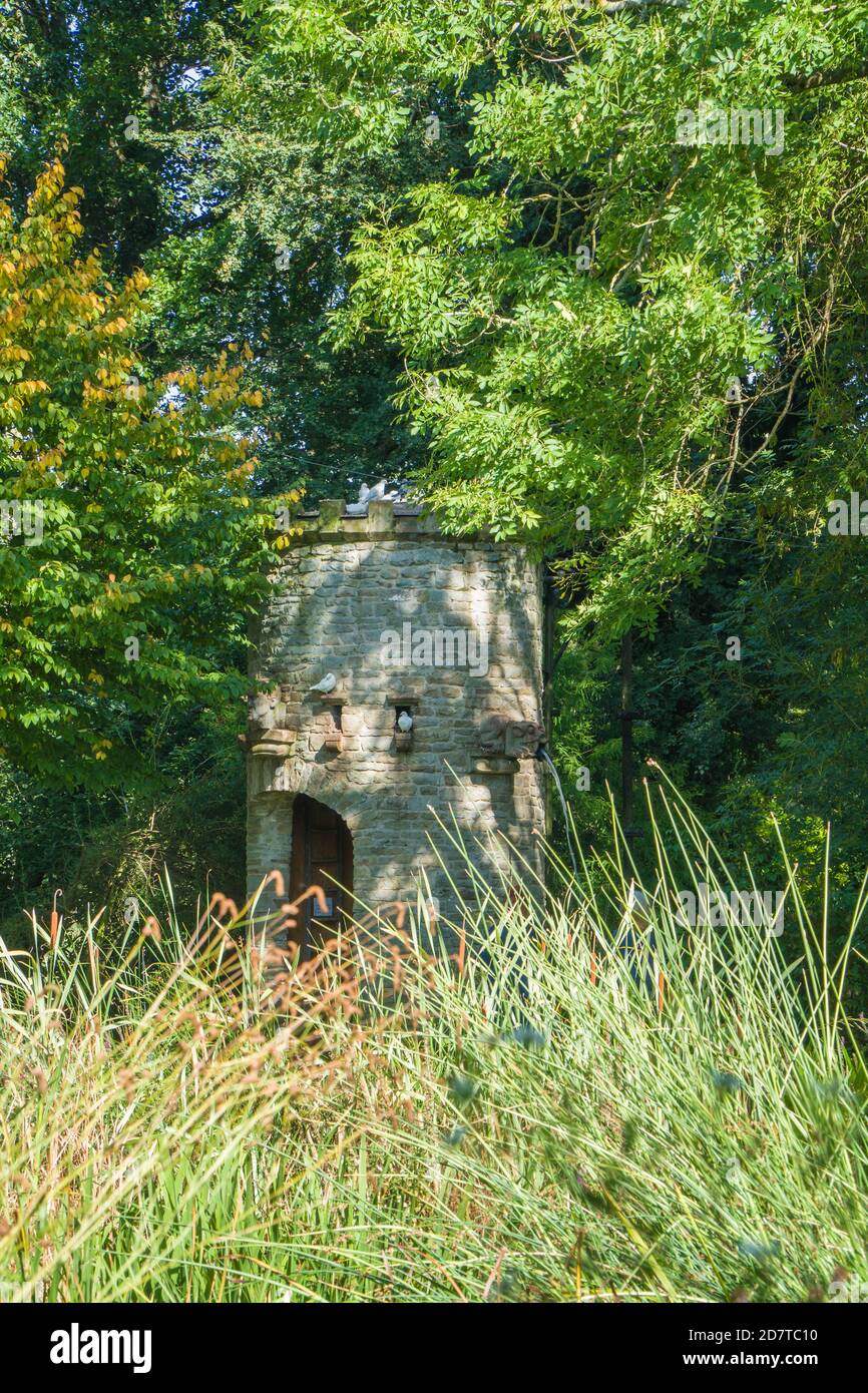 Torre de agua de piedra que escupe agua de una gárgola, Westonbury Mill Water Gardens, Herefordshire Reino Unido. Septiembre de 2020 Foto de stock